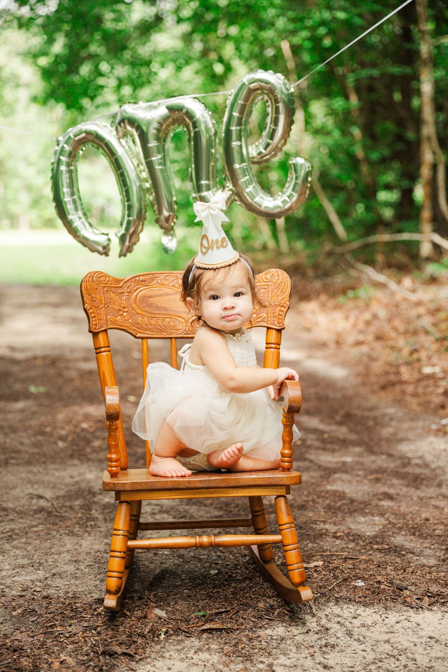 Wooden rocking chair with gold balloon decorations in wooded outdoor setting.