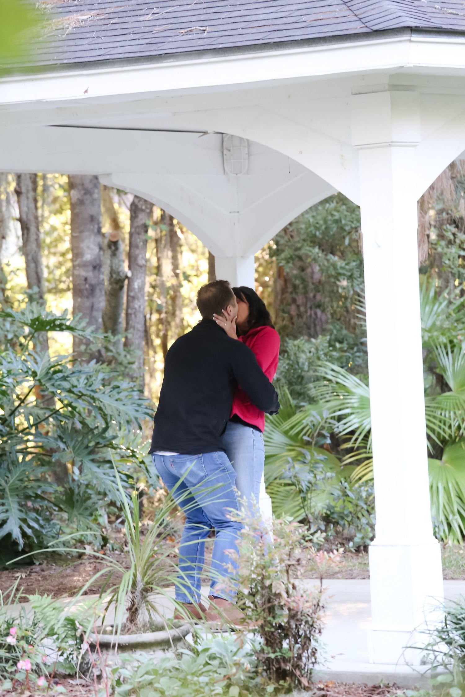 Romantic moment between couple under white gazebo surrounded by palm plants.