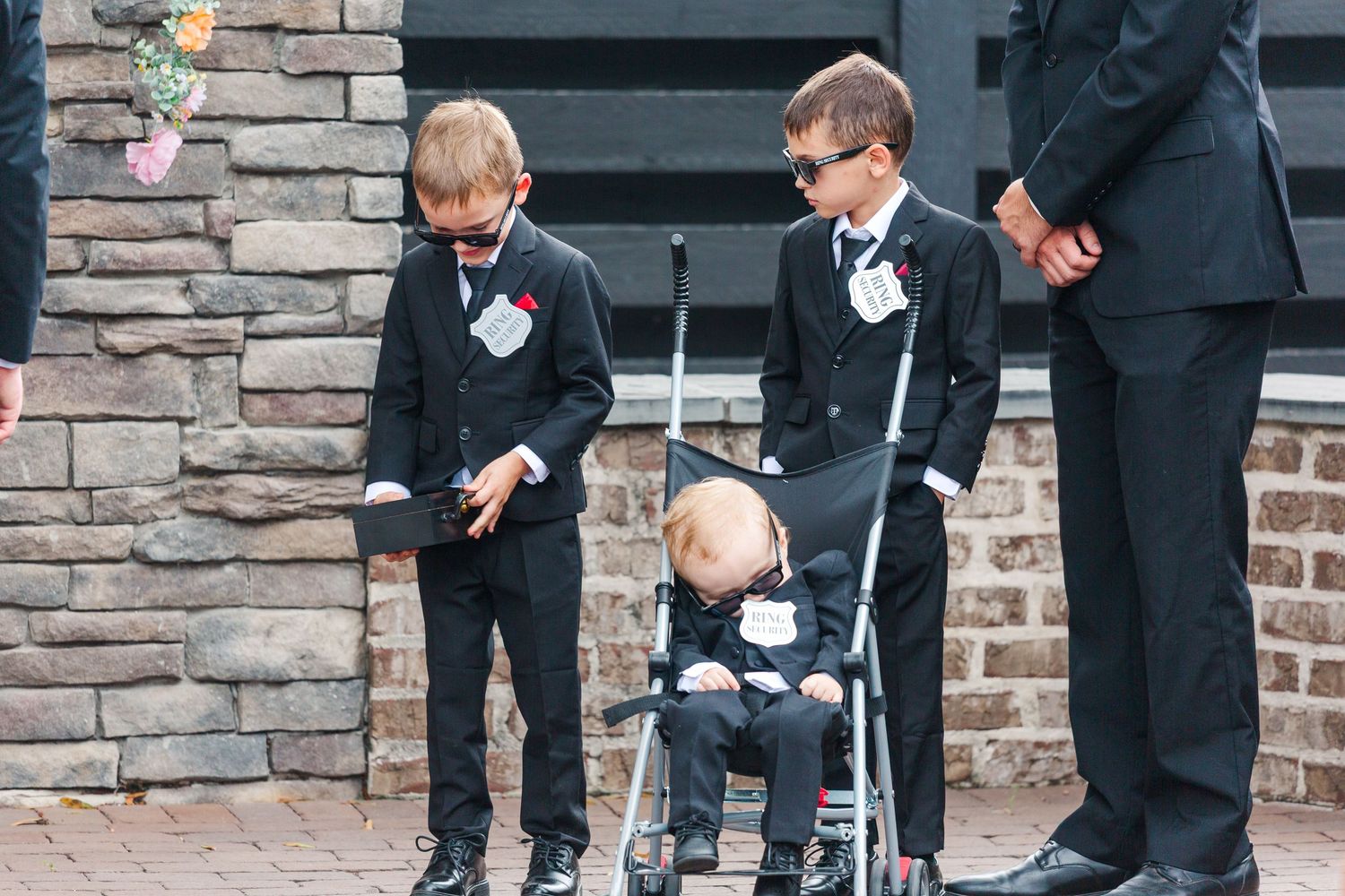 Young ring bearers in formal attire at outdoor wedding ceremony.