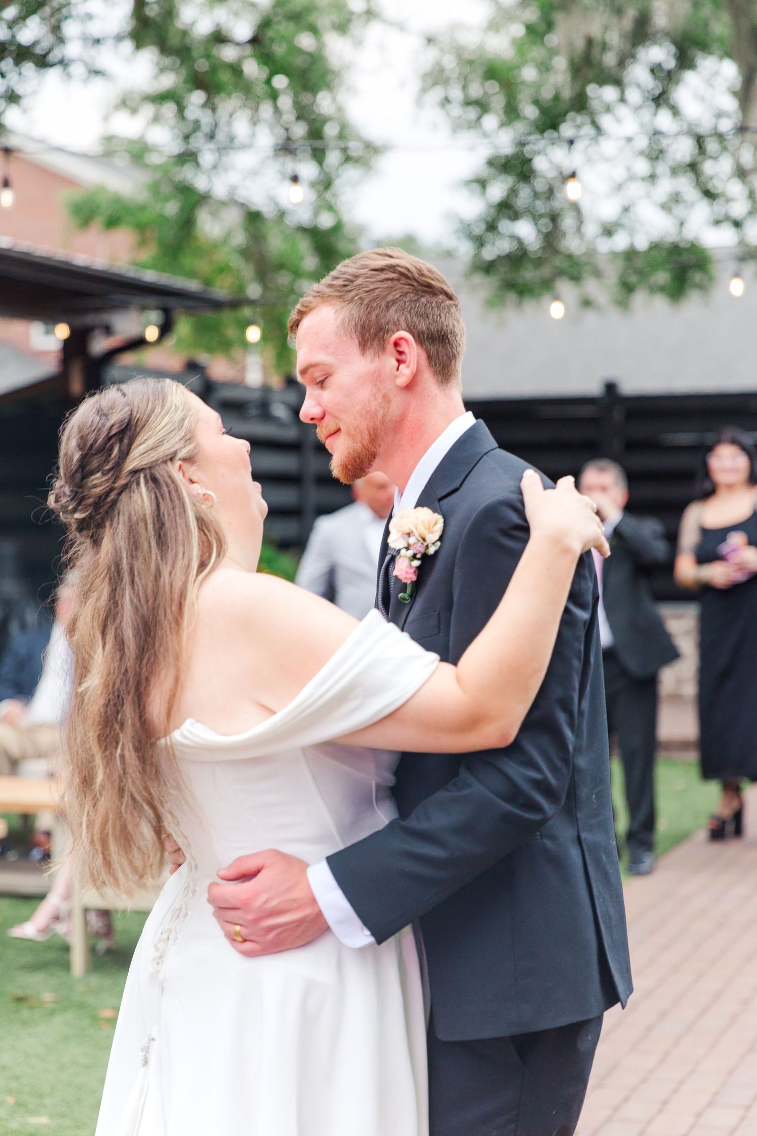 Couple sharing first dance at outdoor wedding reception.