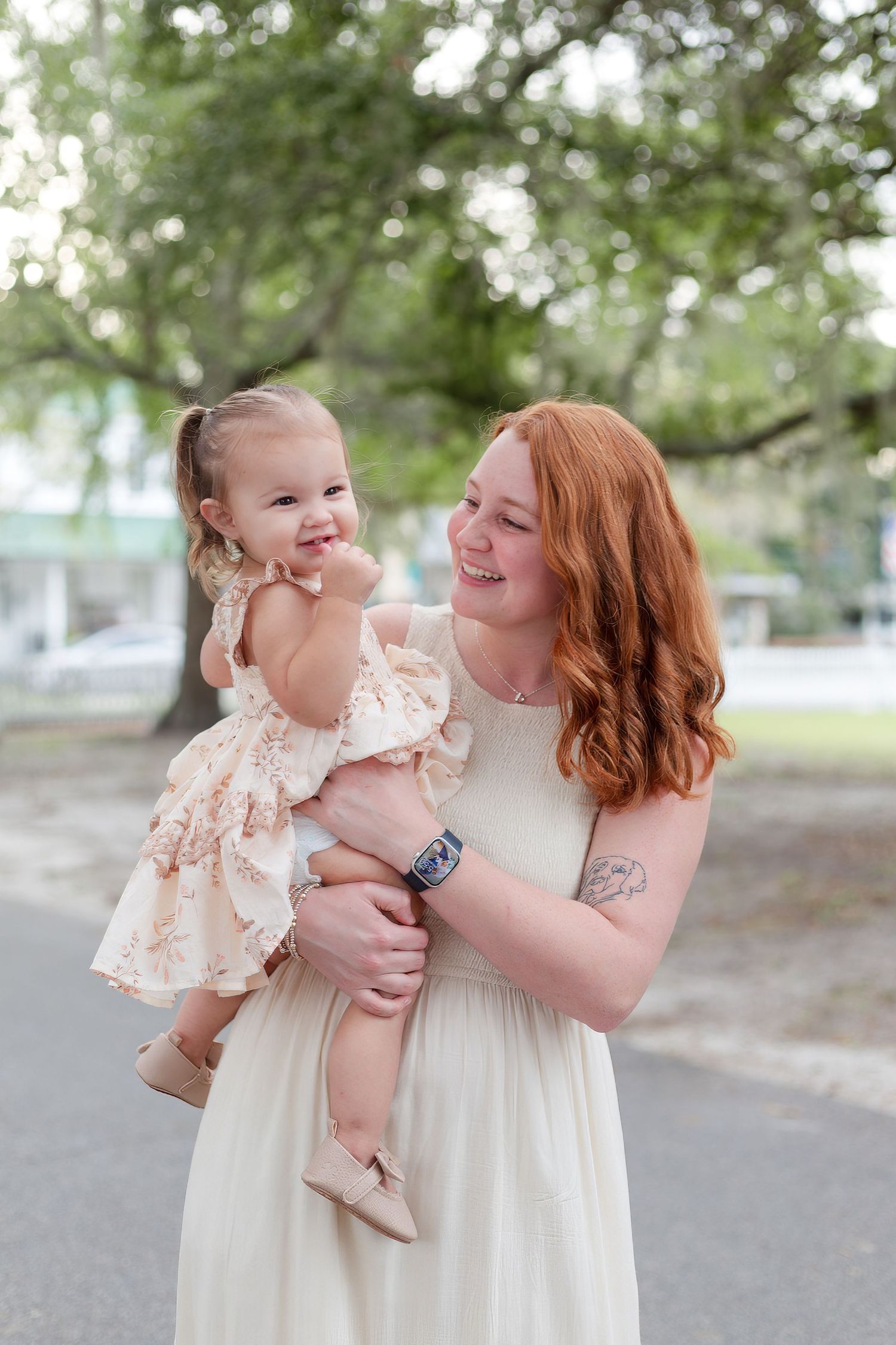 A tender moment captured outdoors under moss-draped trees.