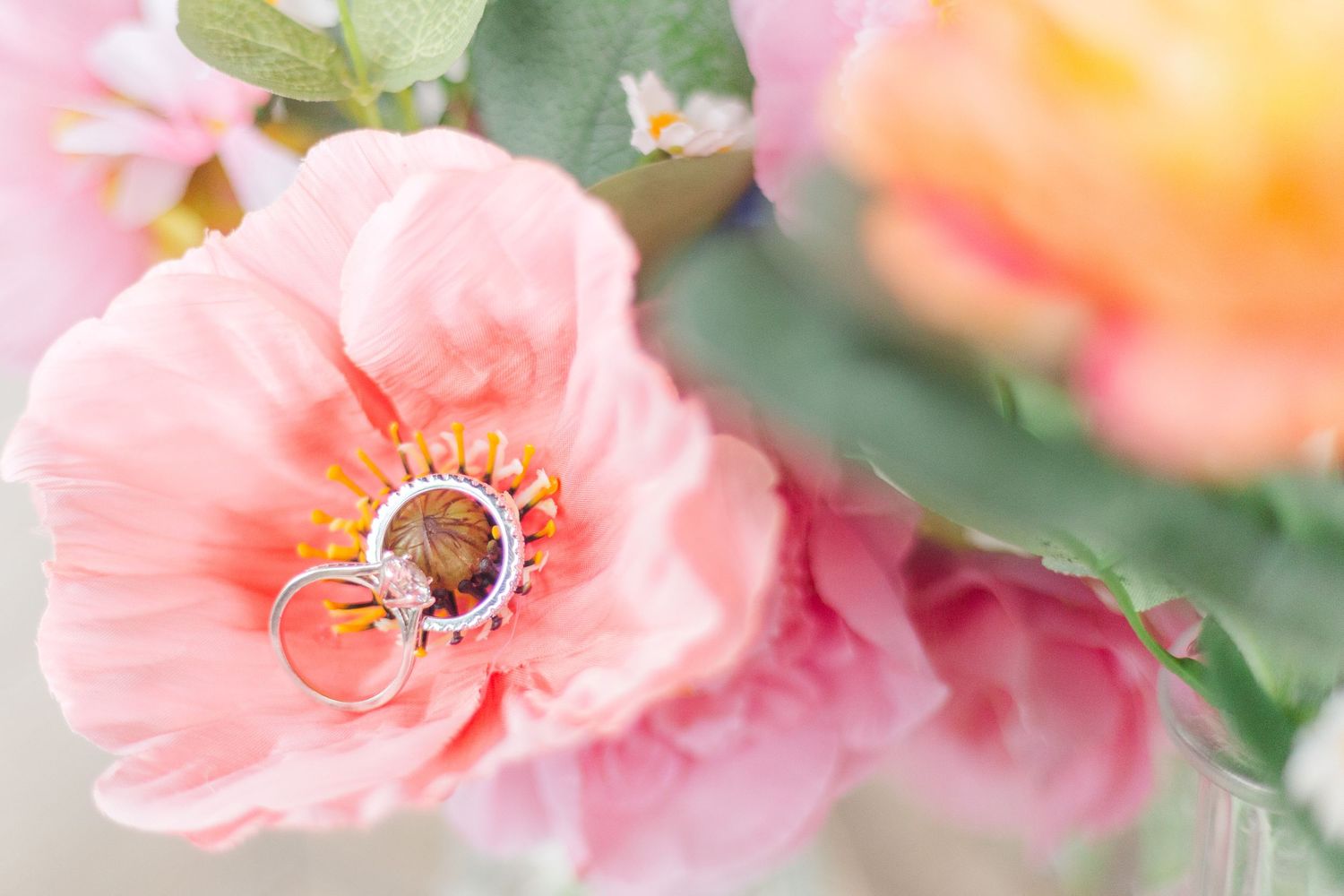 Close-up of wedding rings nestled among pink and coral flowers.