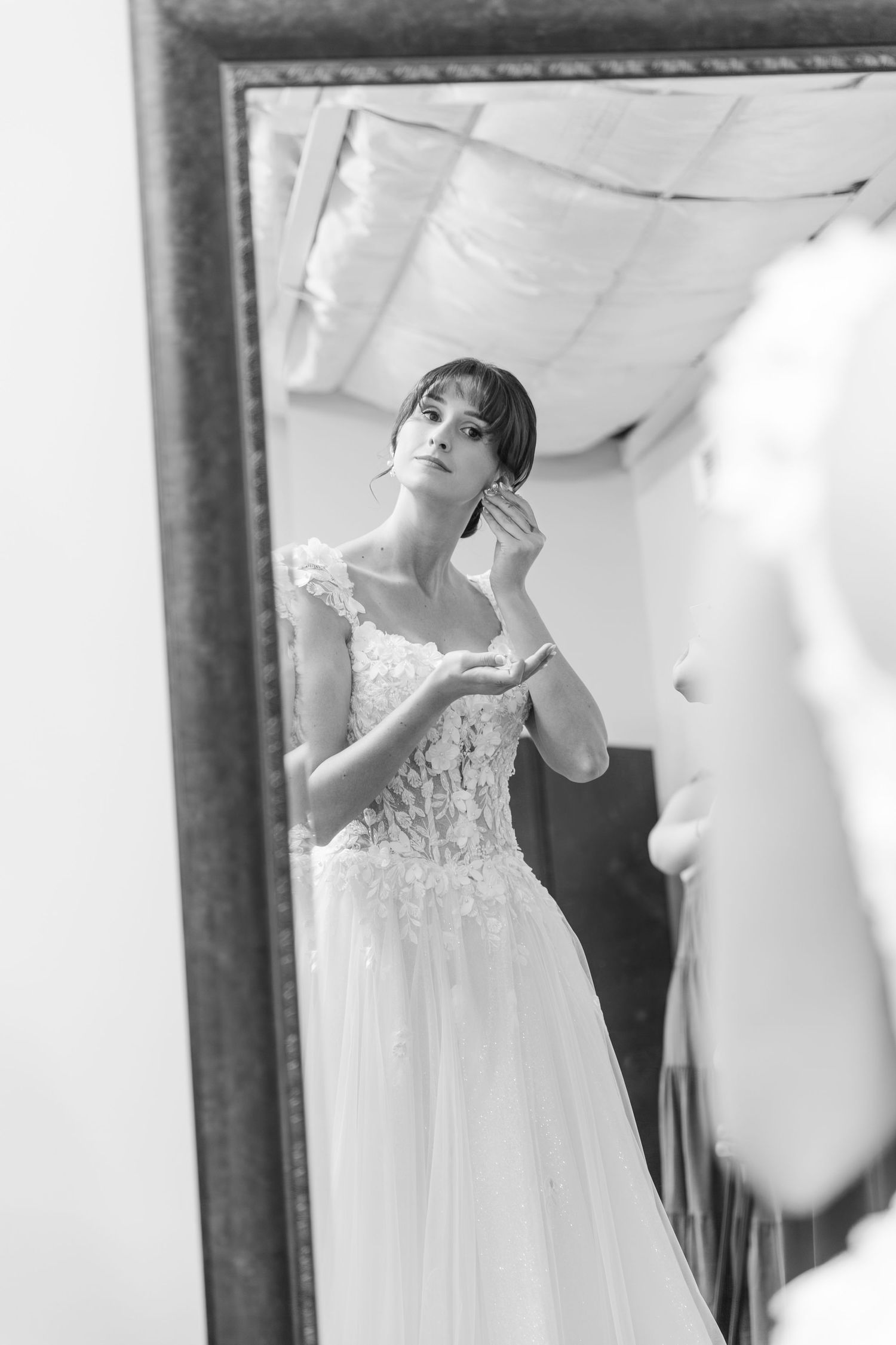 Black and white reflection of bride getting ready in mirror.