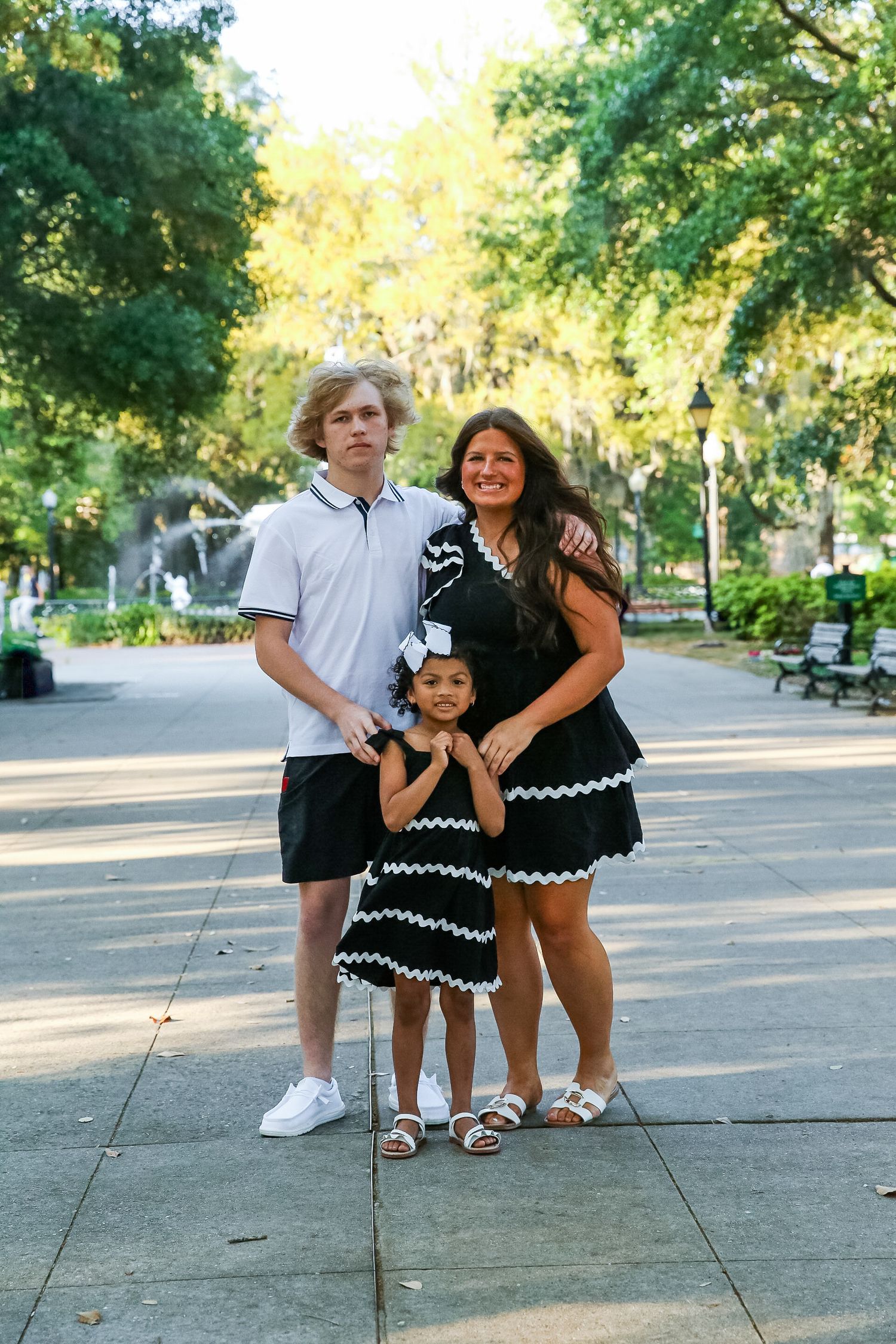 A summer portrait in a sunlit park with trees in the background.