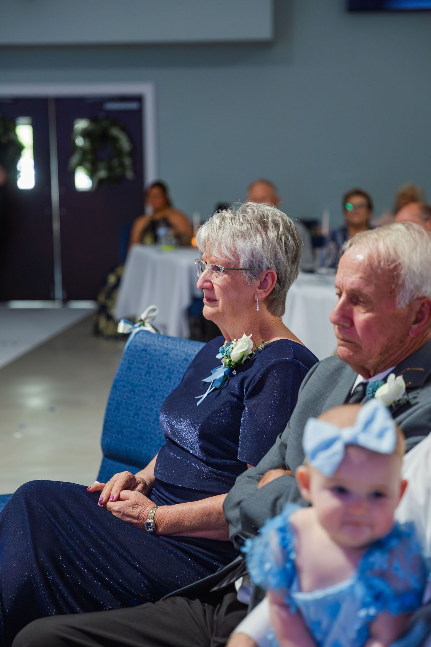 Wedding guests seated in blue chairs watching the ceremony.