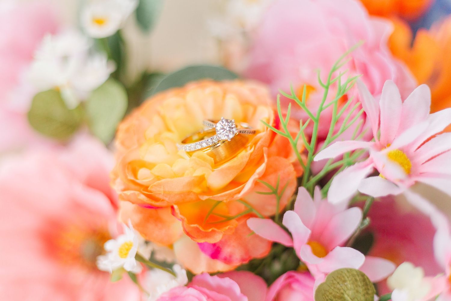 Delicate floral arrangement featuring pink and orange blooms with wedding details.