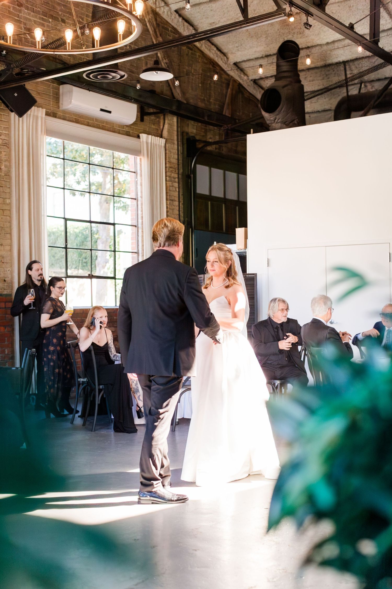 Wedding reception in industrial venue with exposed brick and large windows.