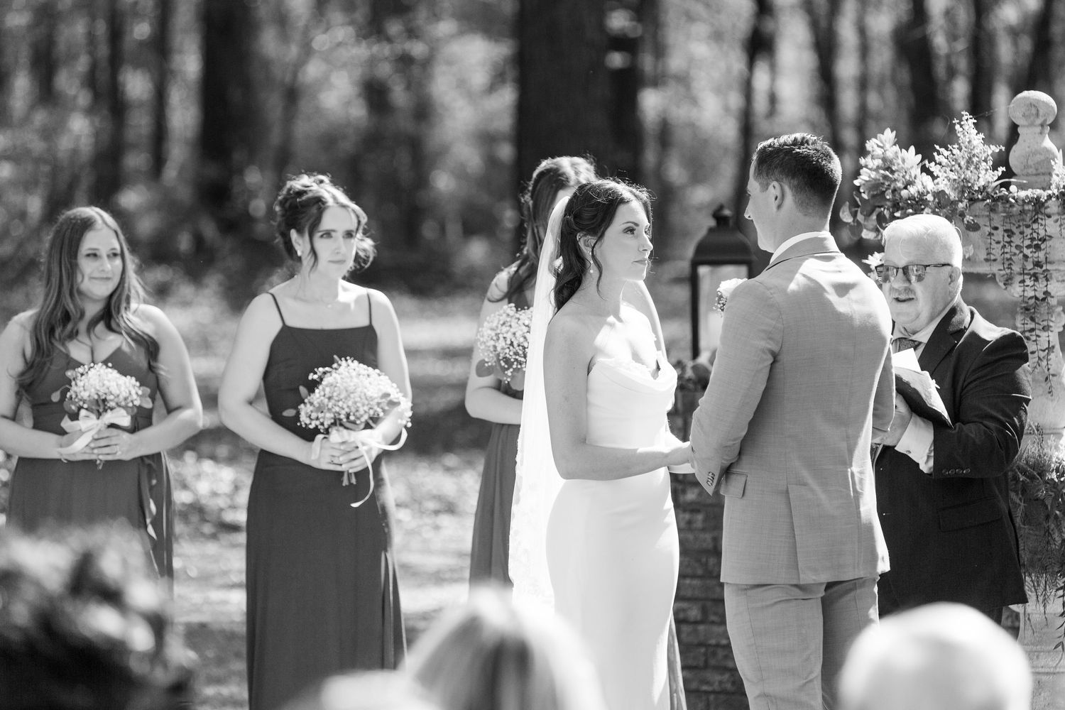 Black and white photo of wedding party celebrating outdoors with joyful expressions.