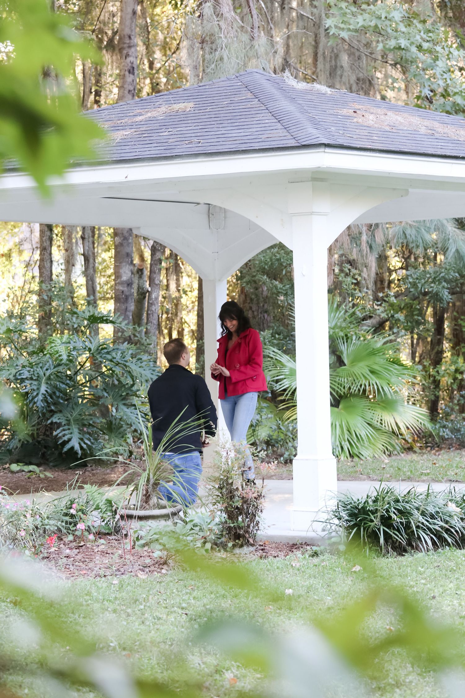 White gazebo in garden setting with couple and lush tropical landscaping.