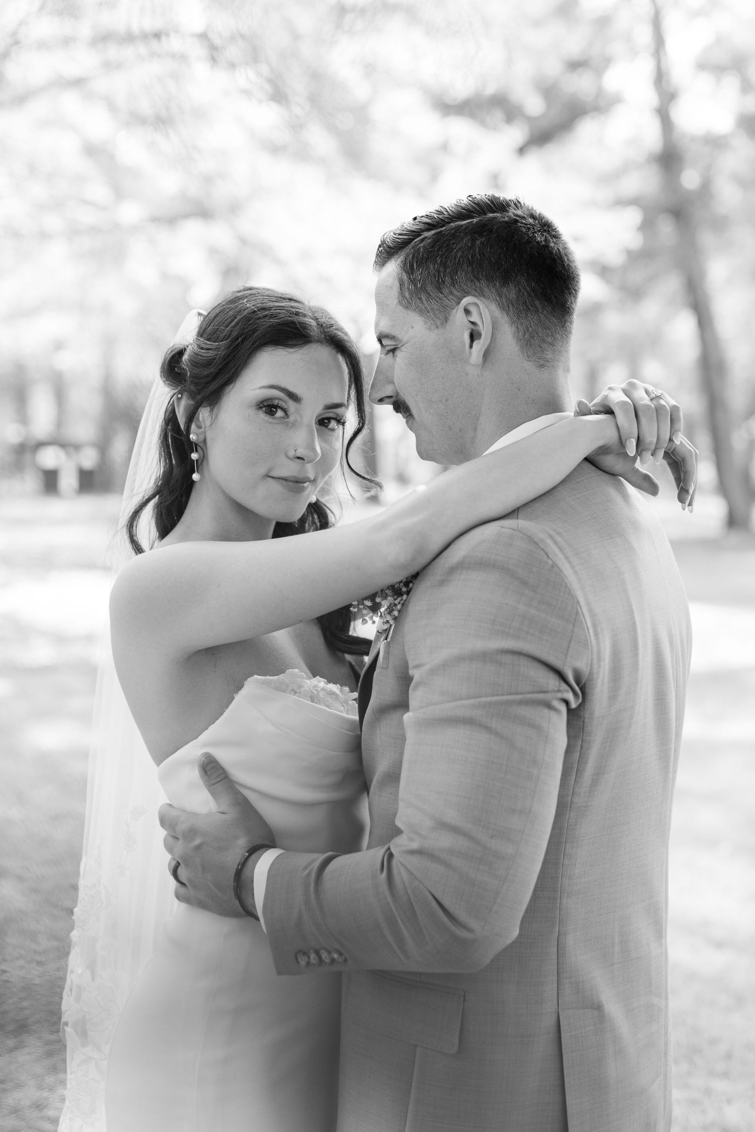 Intimate black and white portrait of couple embracing during outdoor wedding photoshoot.