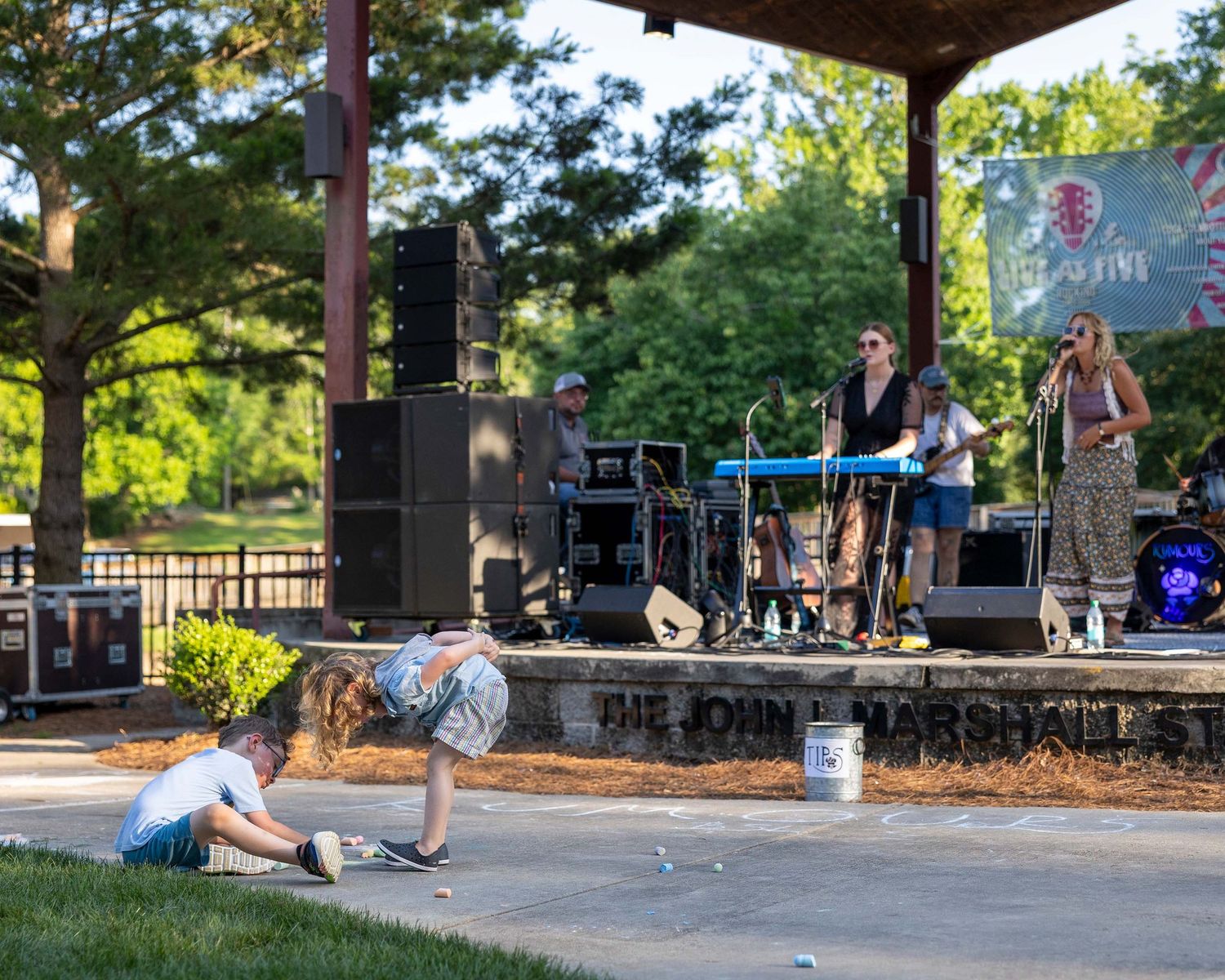 Live band performing on John Marshall Park stage at outdoor summer concert.