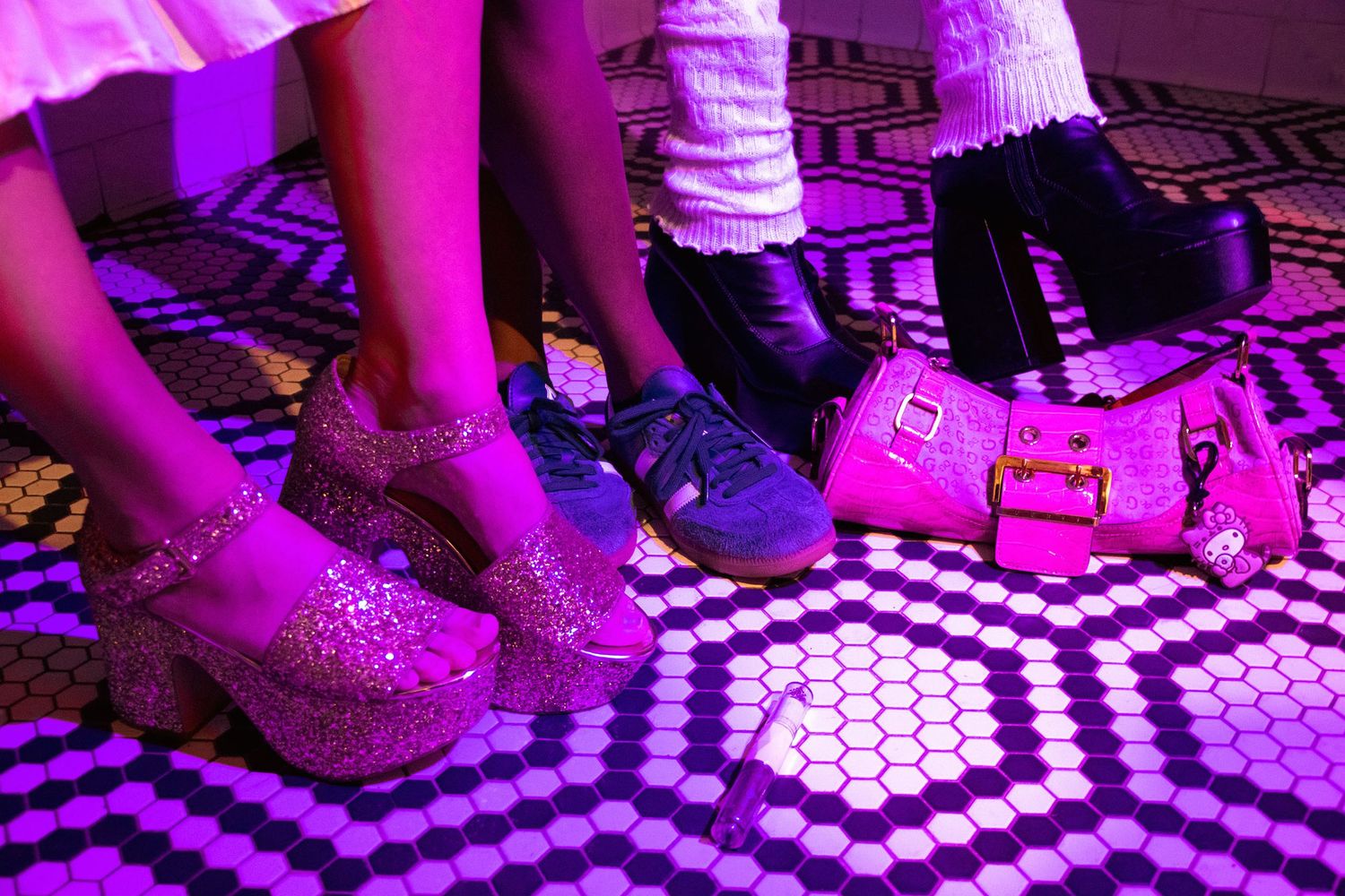 Three people stand on a hexagon-tiled floor wearing colorful platform and chunky shoes.