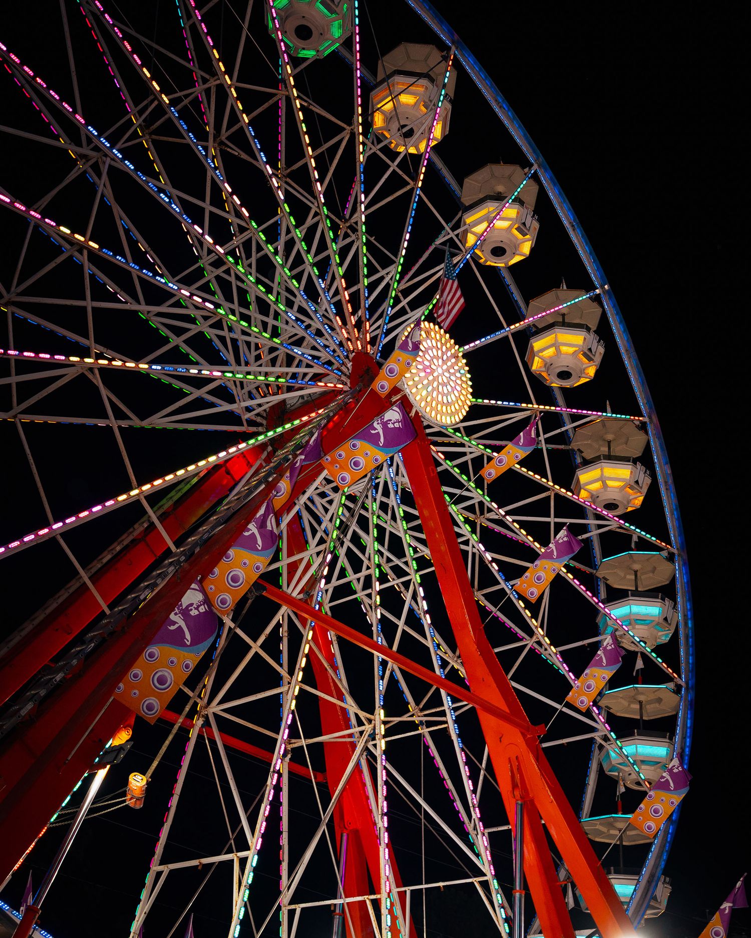 Colorful illuminated Ferris wheel spinning against a dark night sky.
