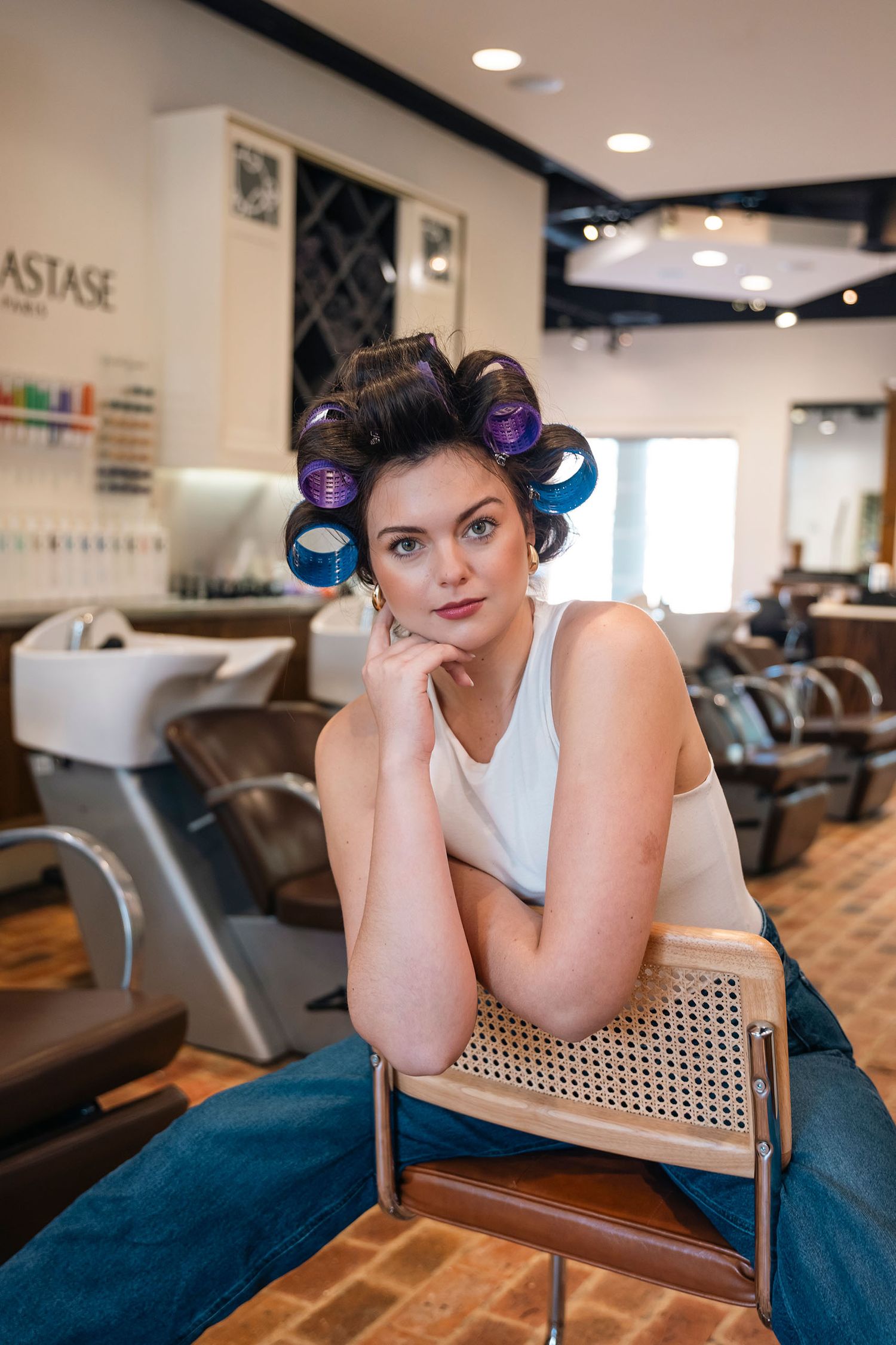 Woman with purple hair rollers sitting confidently in a salon chair waiting for her style.