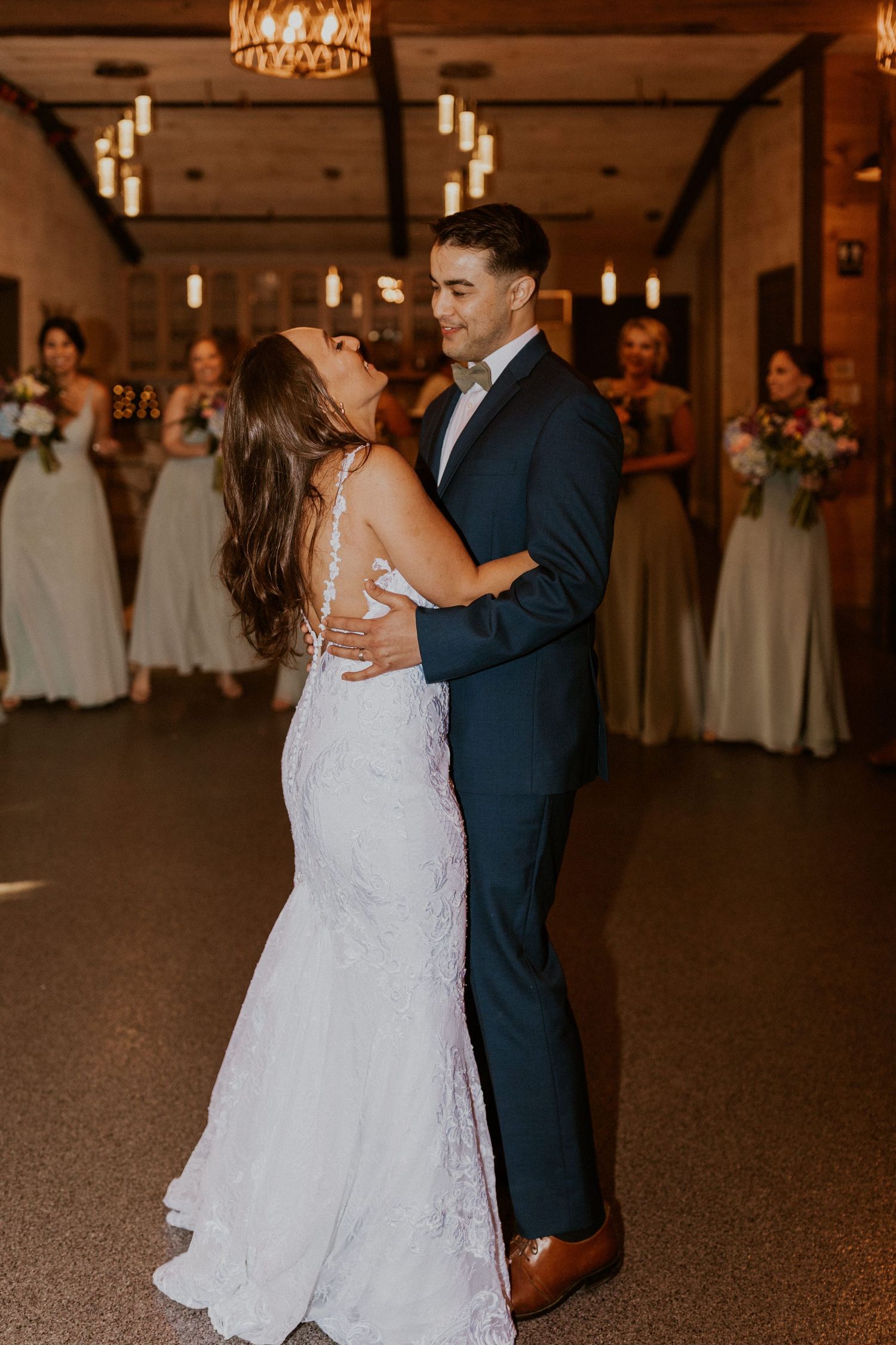 Romantic first dance moment captured in a rustic barn wedding venue with ambient lighting.