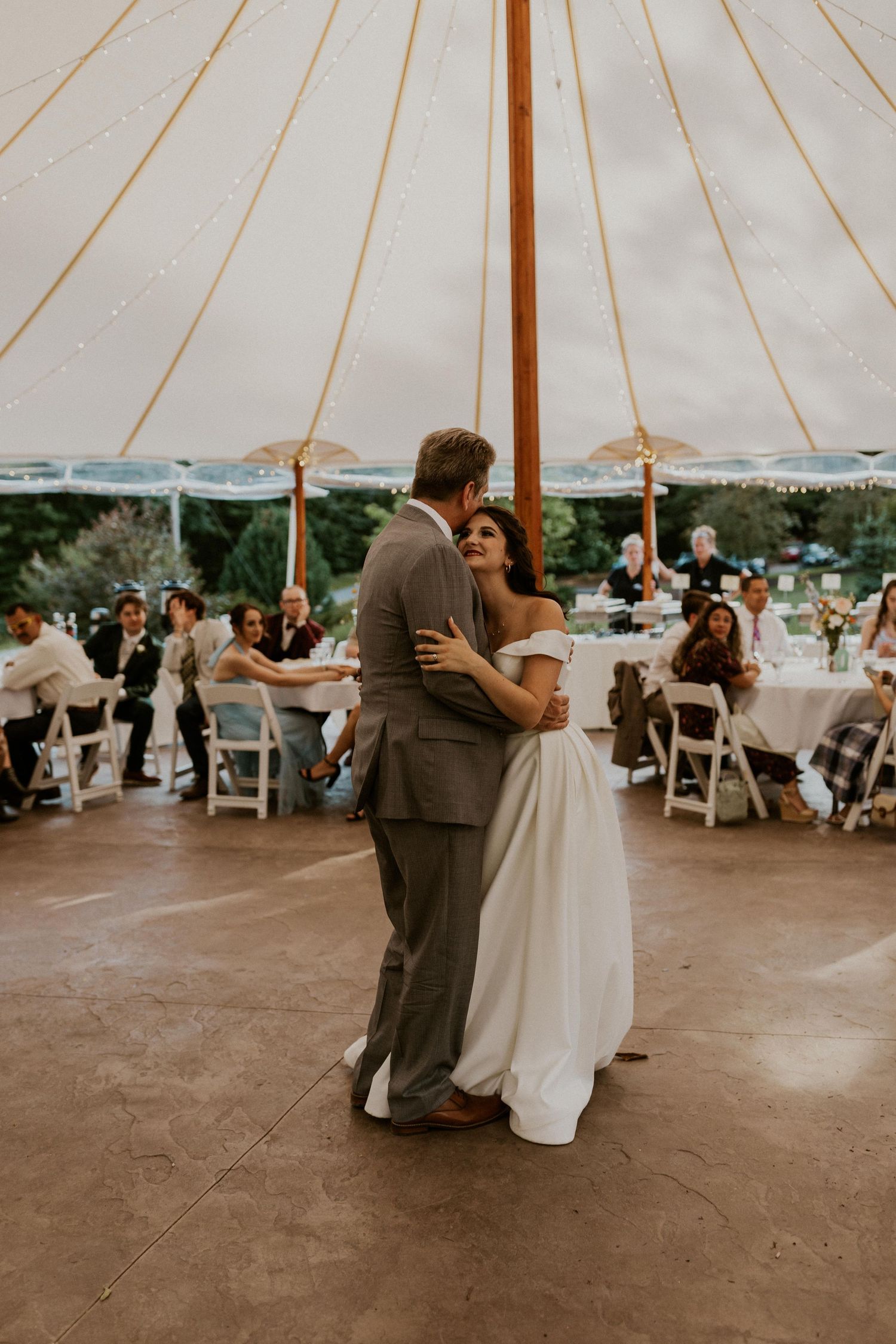 Wedding couples sharing intimate dances under a white tent at an outdoor reception.