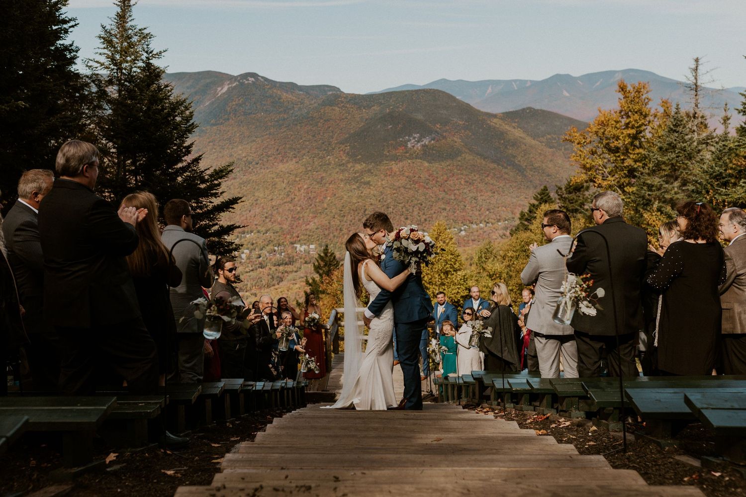 Newlyweds stopping in the center of the aisle on their way out to kiss with the mountain view as a stunning backdrop.