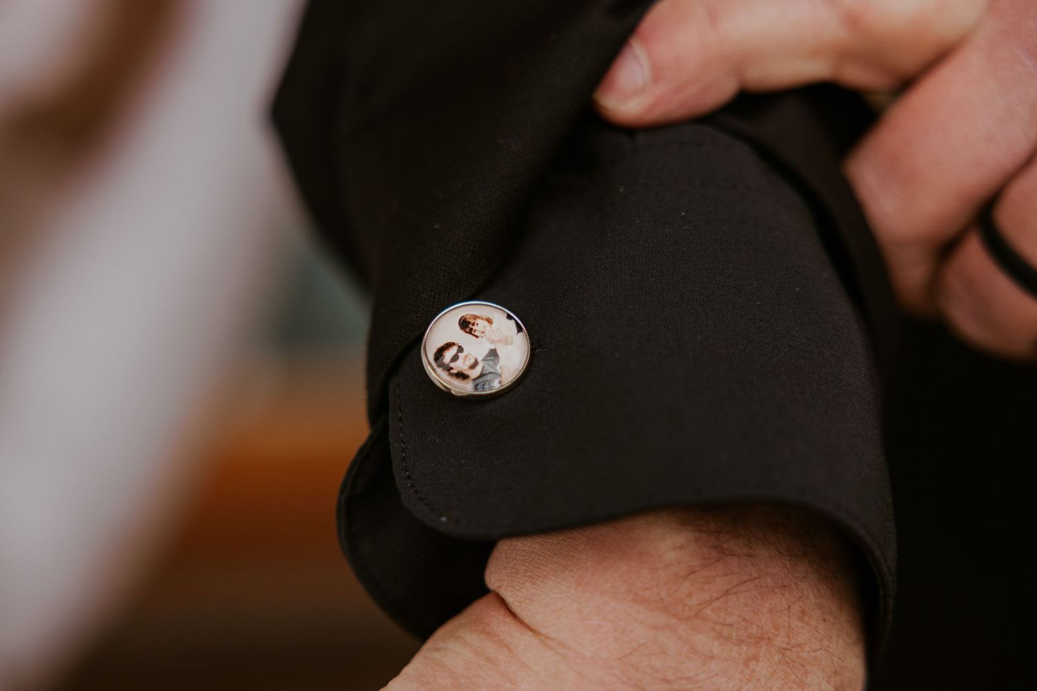 Close-up of a custom photo cufflink on a black suit sleeve, featuring a portrait image in a silver setting.
