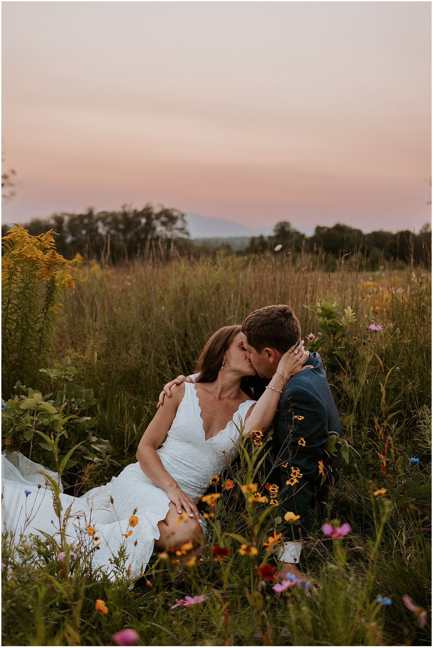 Couple embracing in a wildflower field during golden hour sunset.