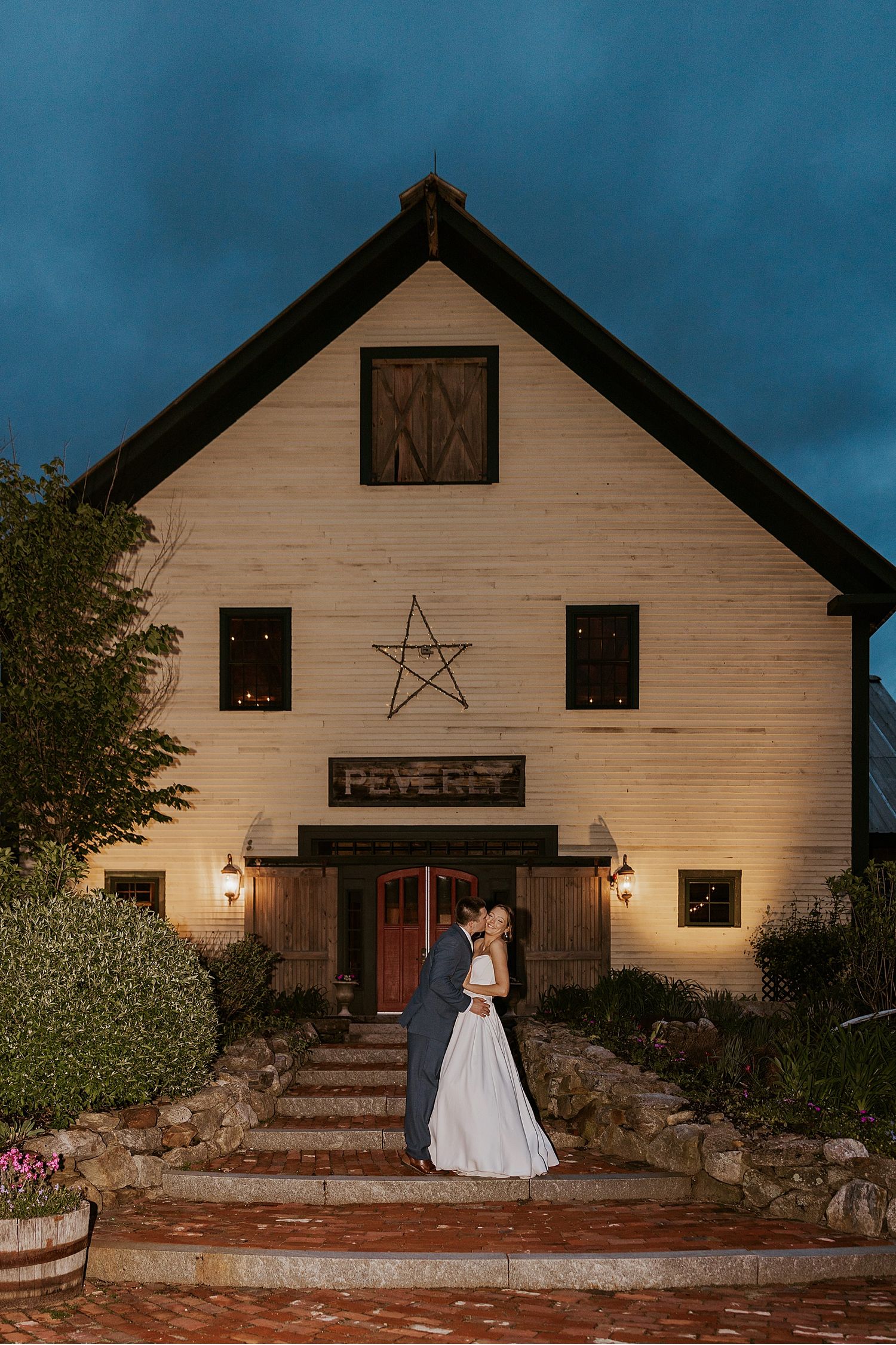 Rustic barn wedding venue illuminated at dusk with decorative star and lanterns.
