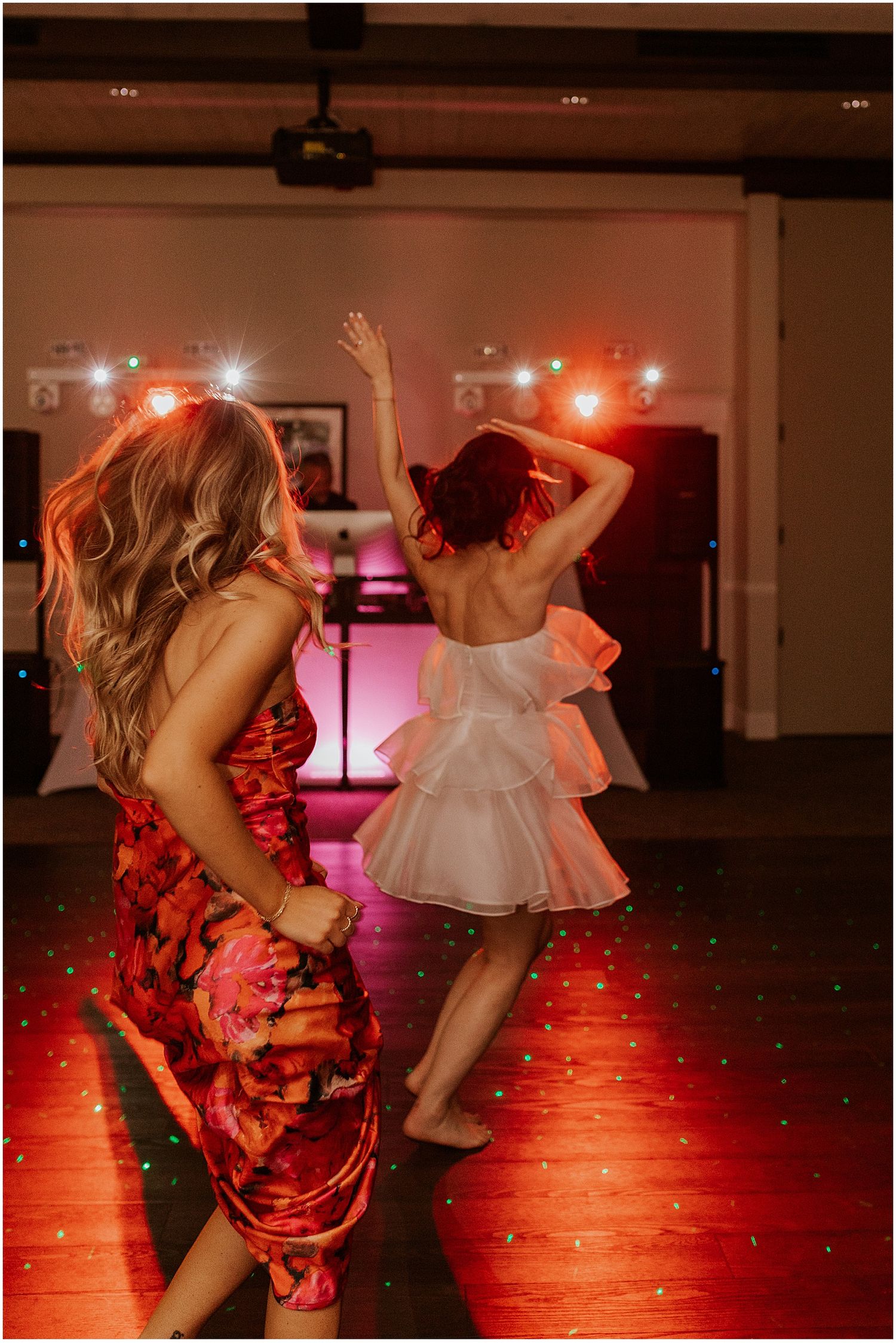 Dancers in white dresses moving energetically under dramatic red lighting at a reception.