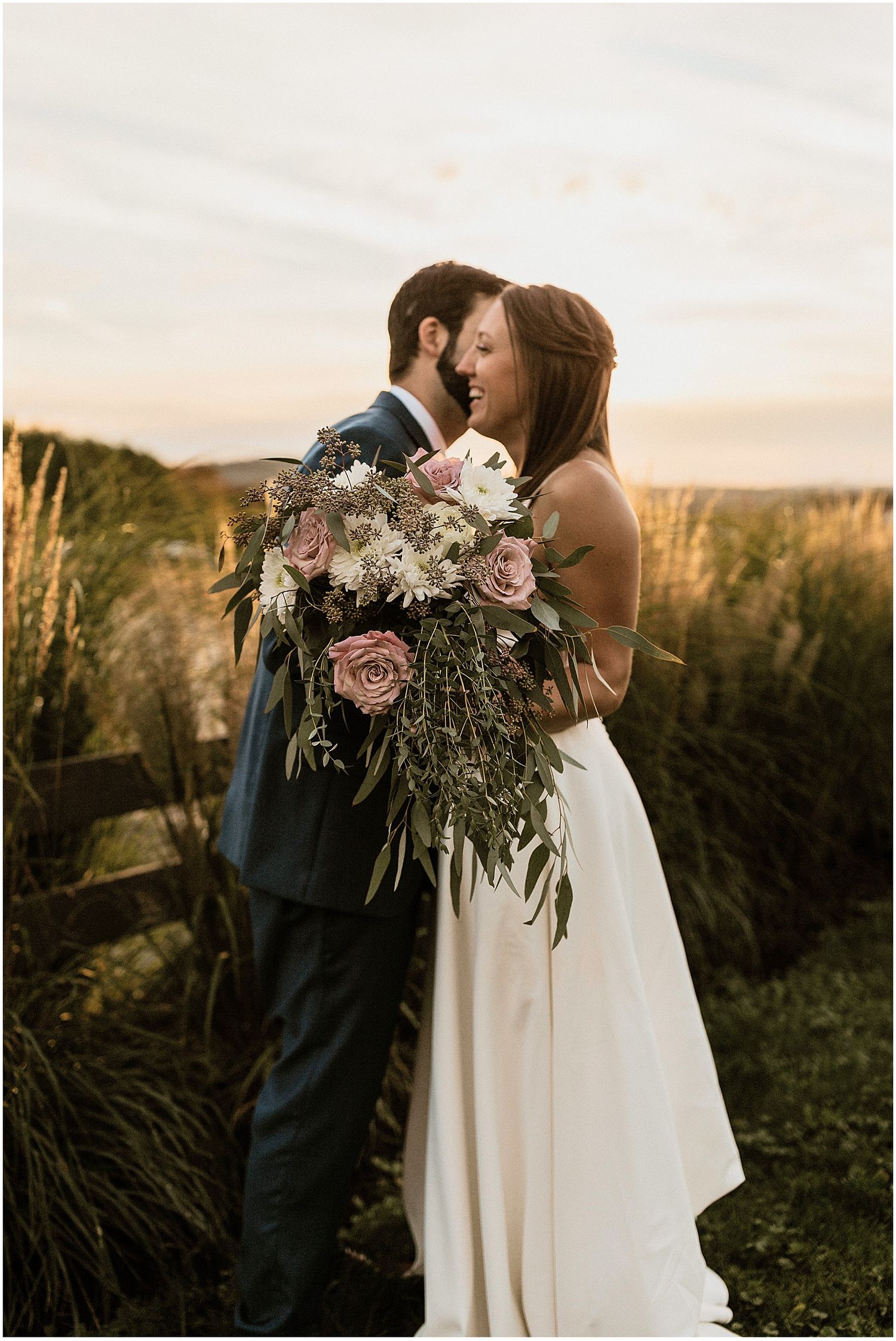 Romantic sunset wedding portrait with soft lighting and elegant floral arrangements in a natural setting.