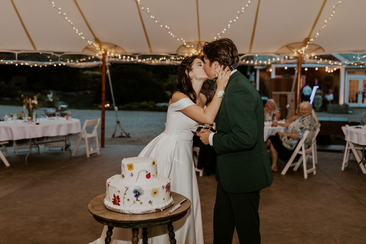 Wedding celebration under string lights with guests dancing and enjoying the festivities.
