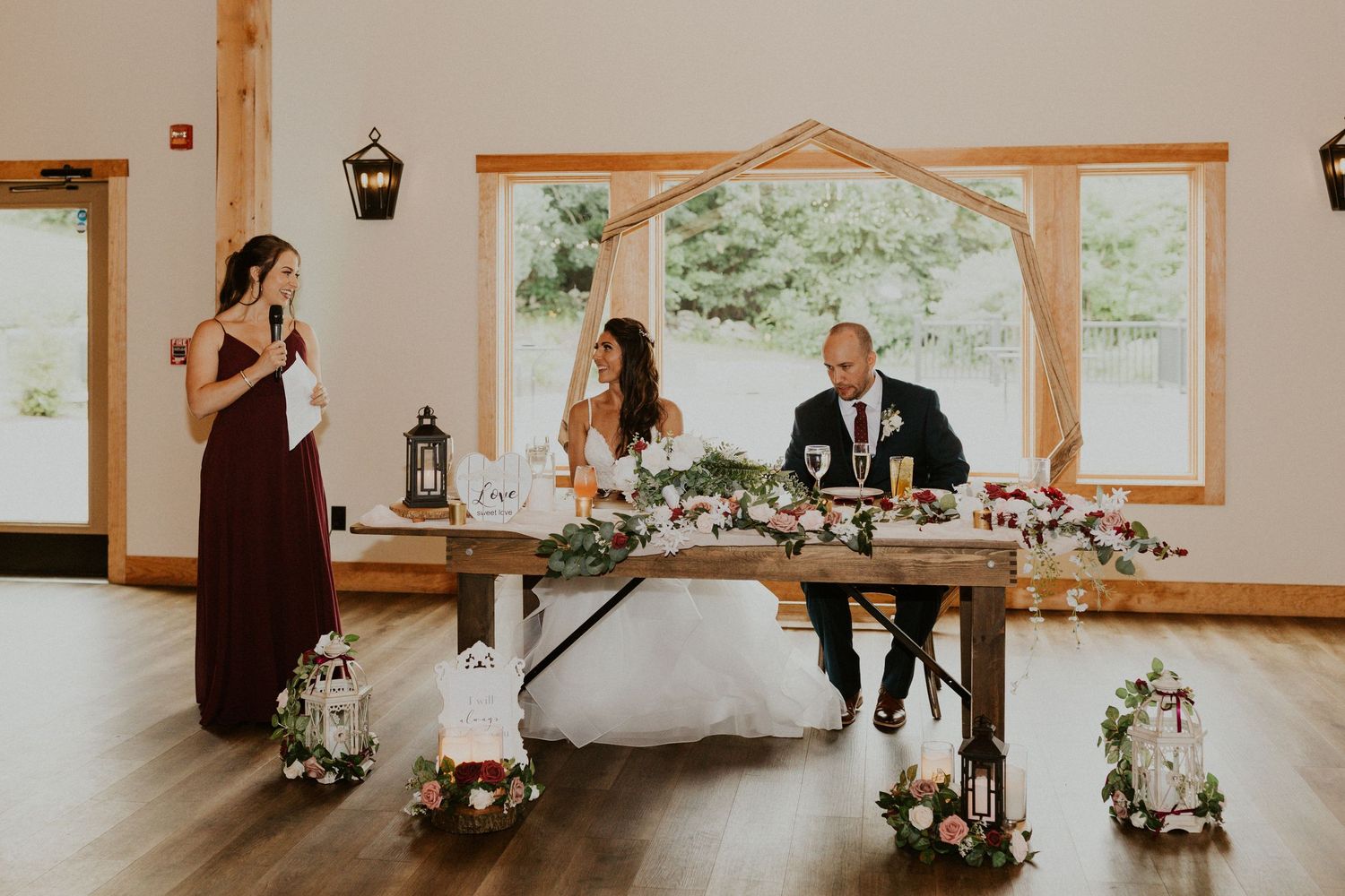 Rustic barn wedding venue with wooden beams and pendant lighting creates warm ambiance.