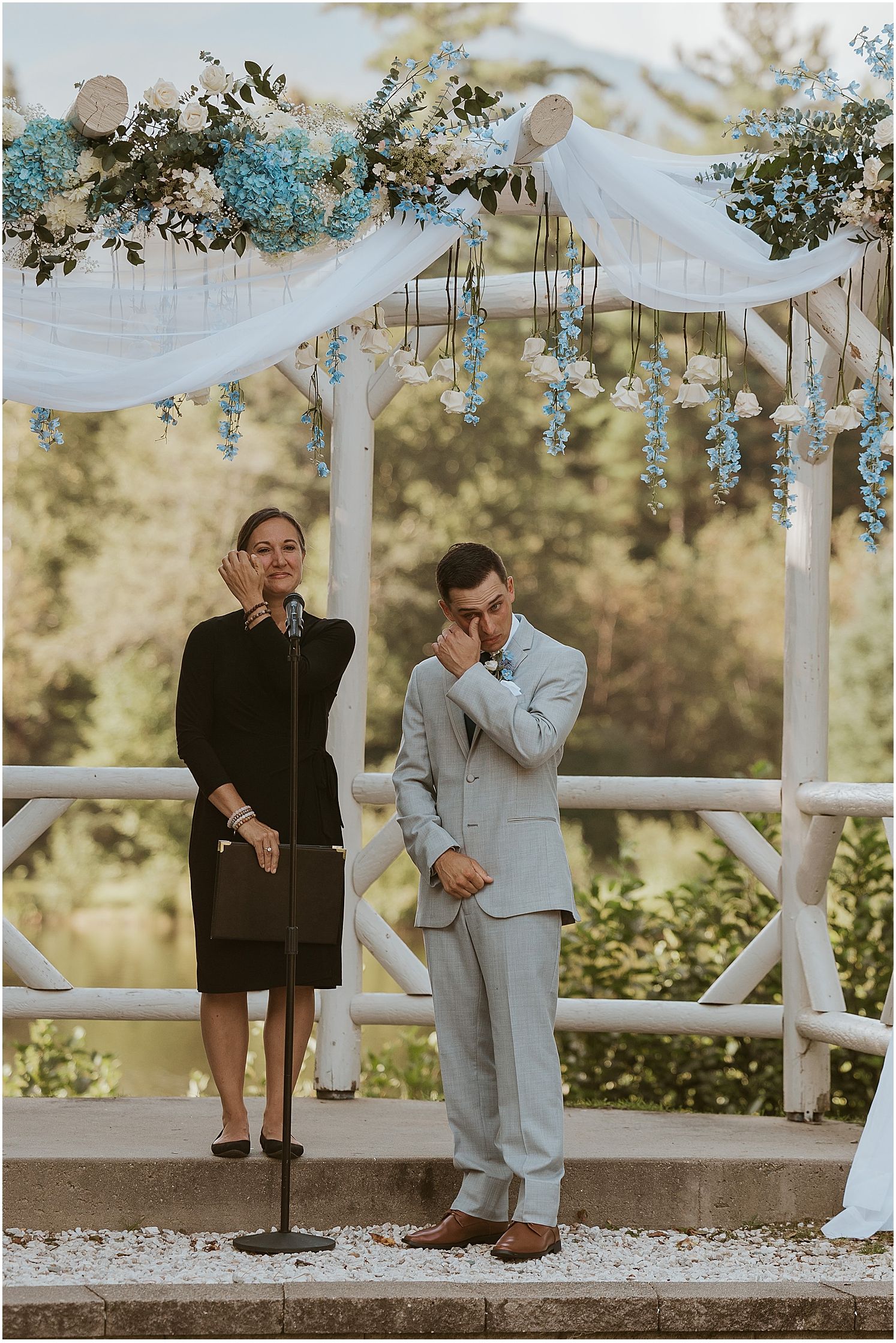 Wedding ceremony setup with white draped gazebo and floral decorations in golden sunlight.