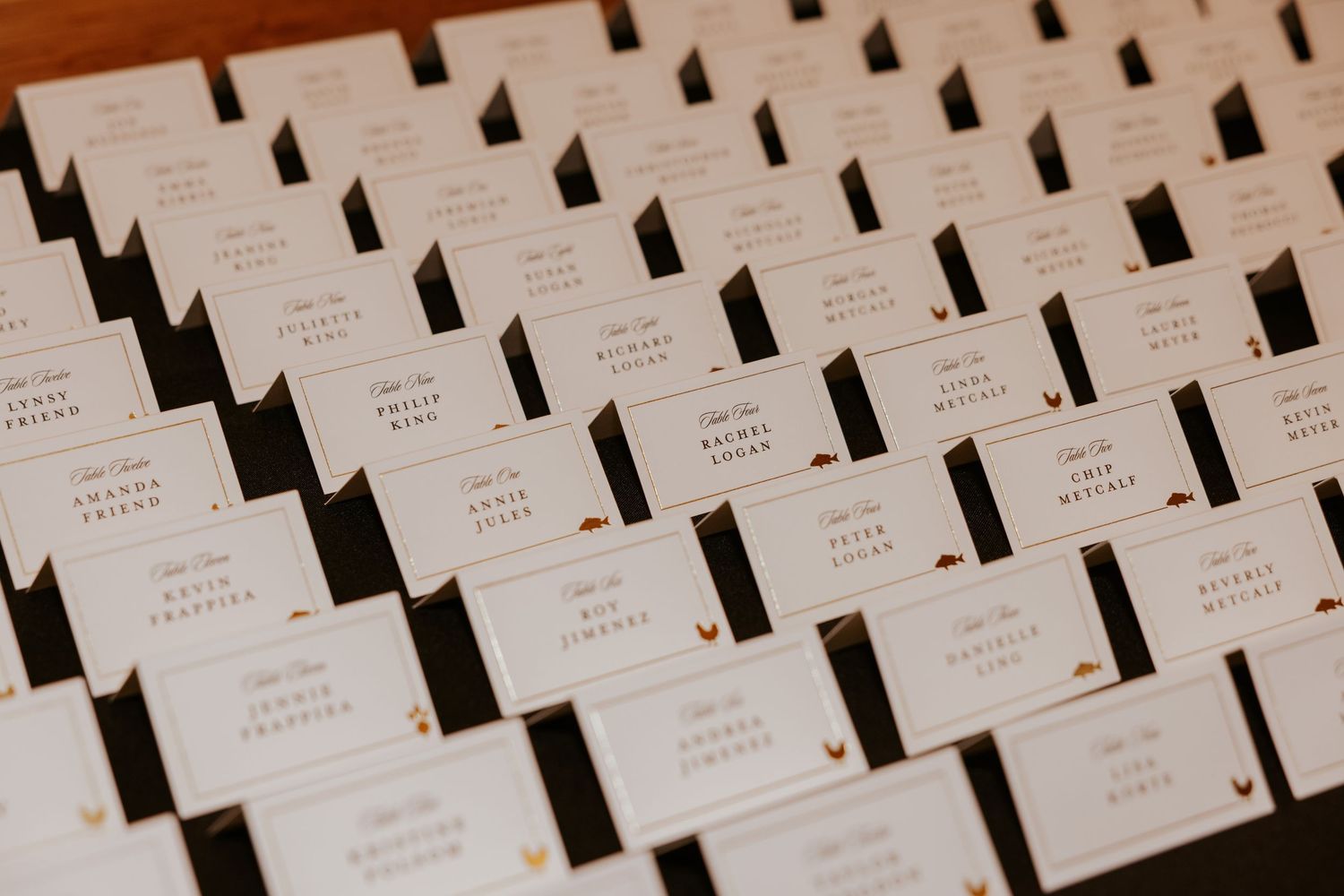 Rows of elegant white place cards arranged neatly on a dark surface for a formal event.