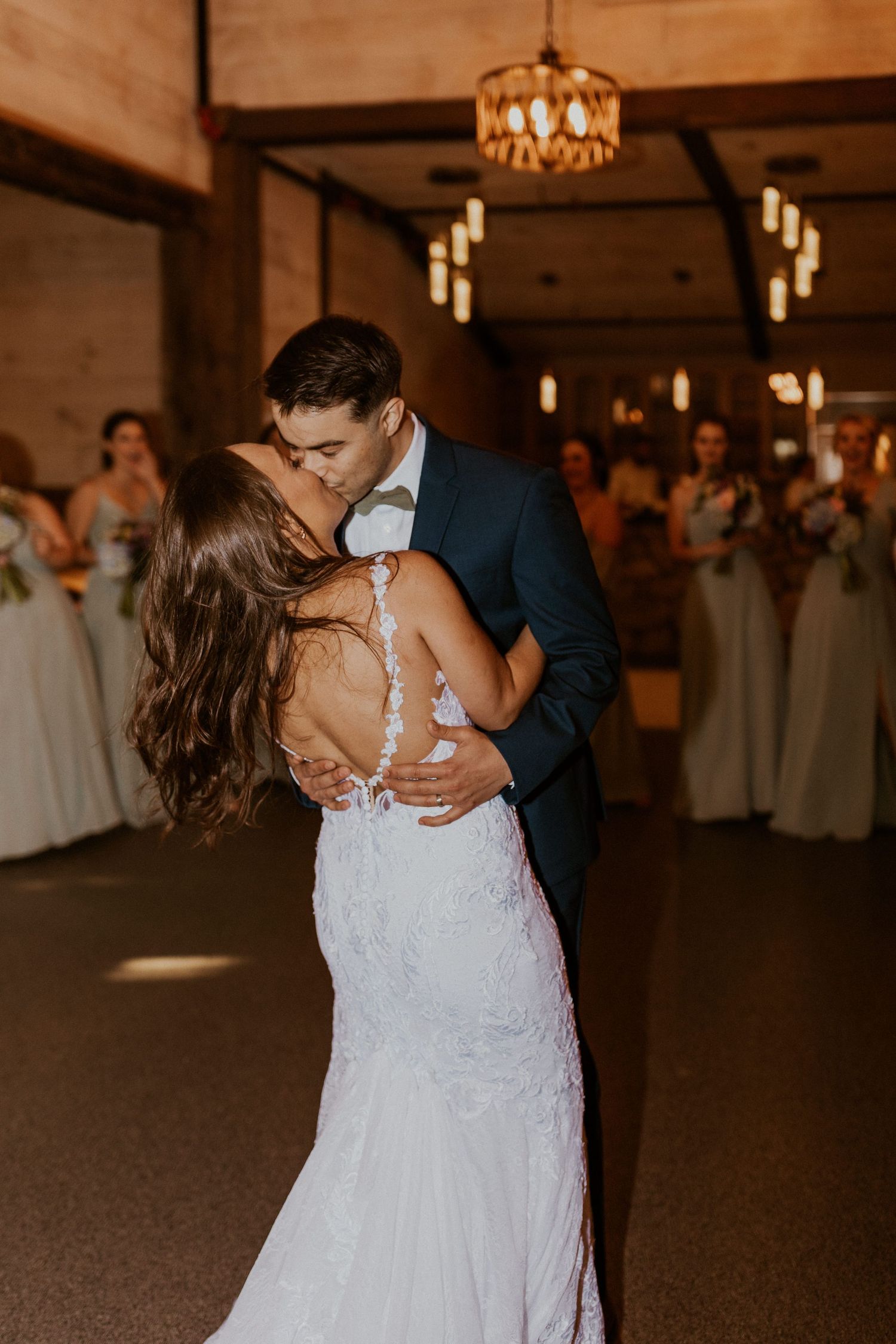 Intimate wedding dance captured in a warmly lit wooden barn reception space.