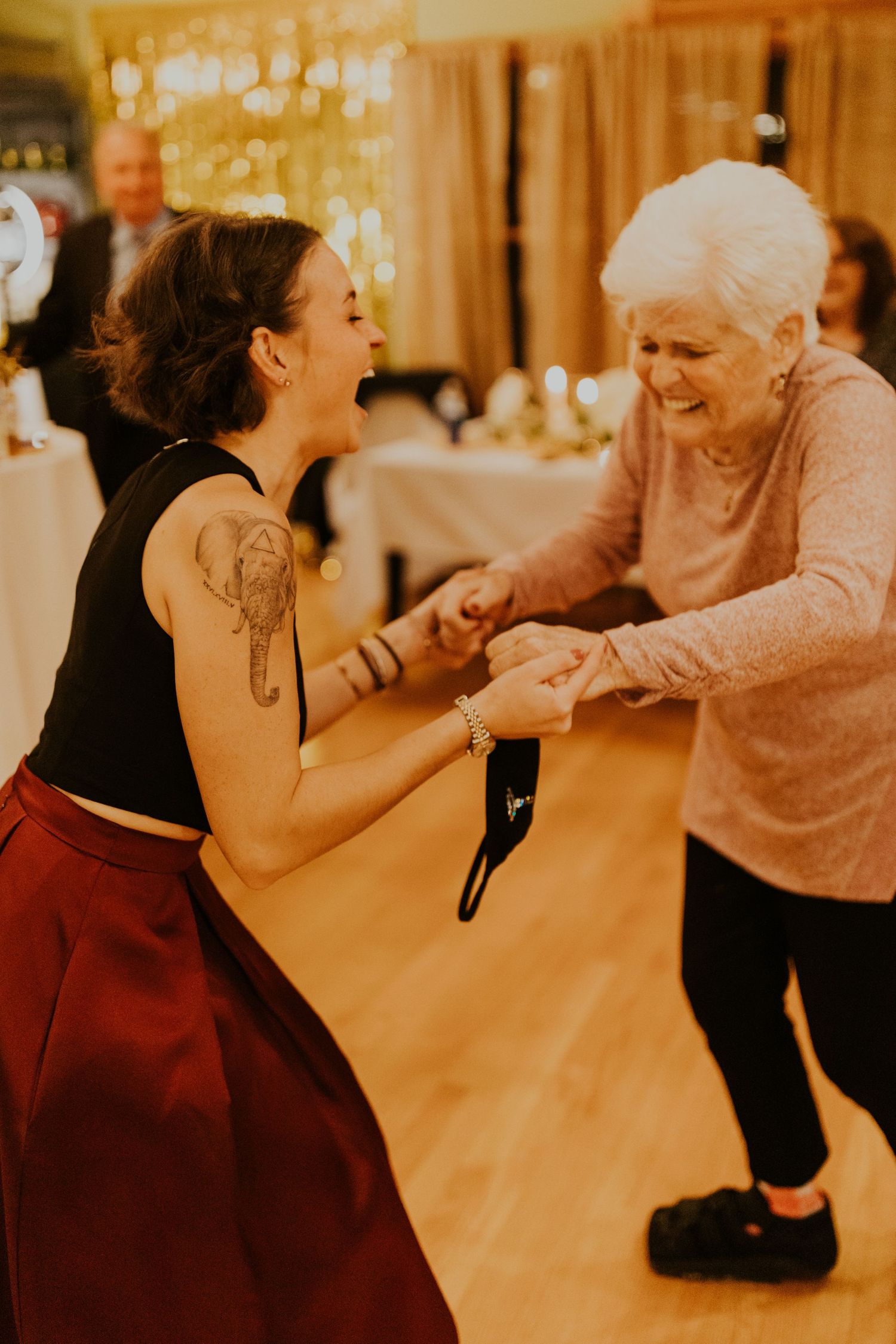 Grandmother and granddaughter dancing together at a wedding, laughing and having a great time together.