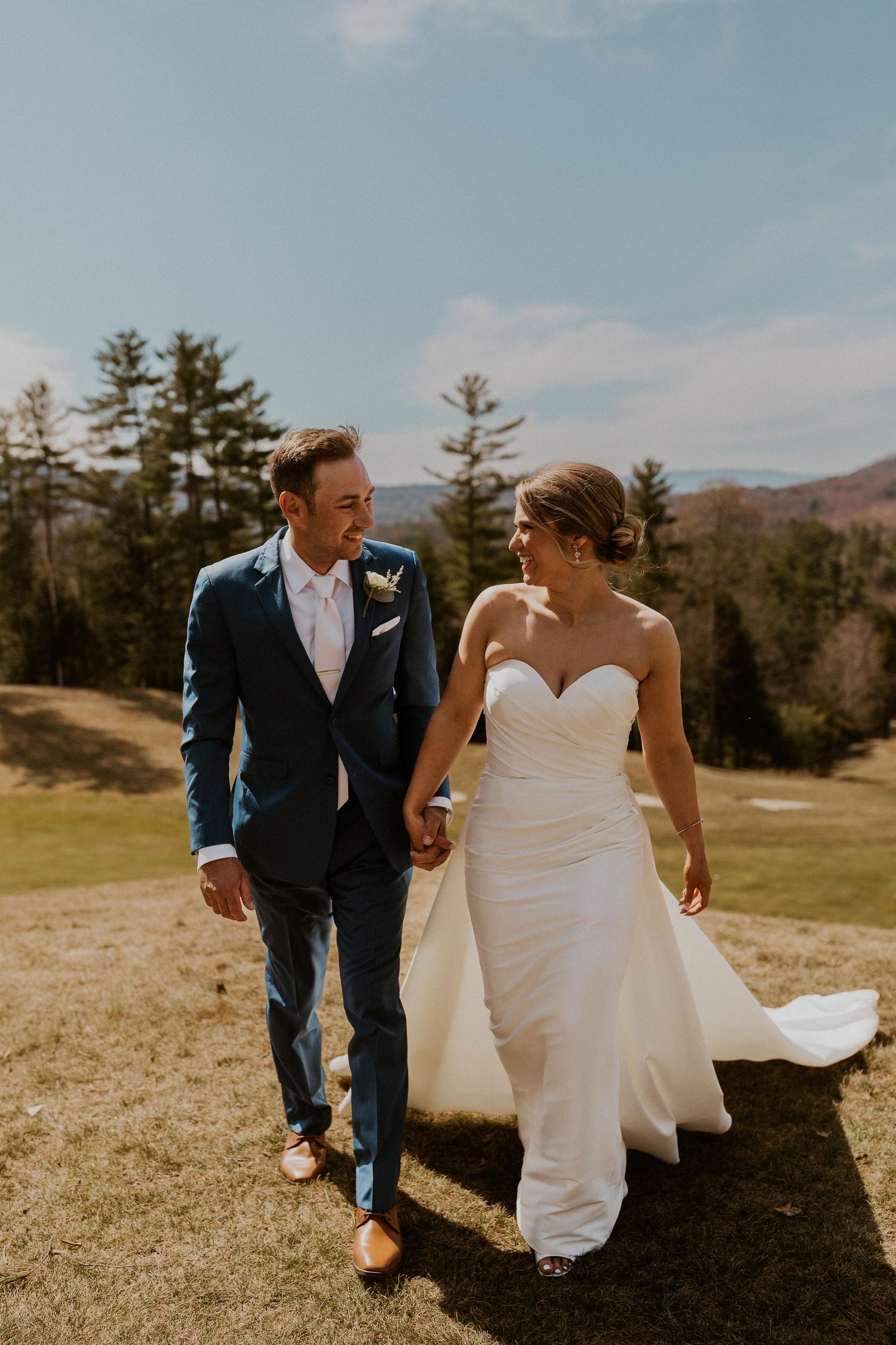 Kendra and Andrew walking together on the sunny golf course at Owl's Nest Resort