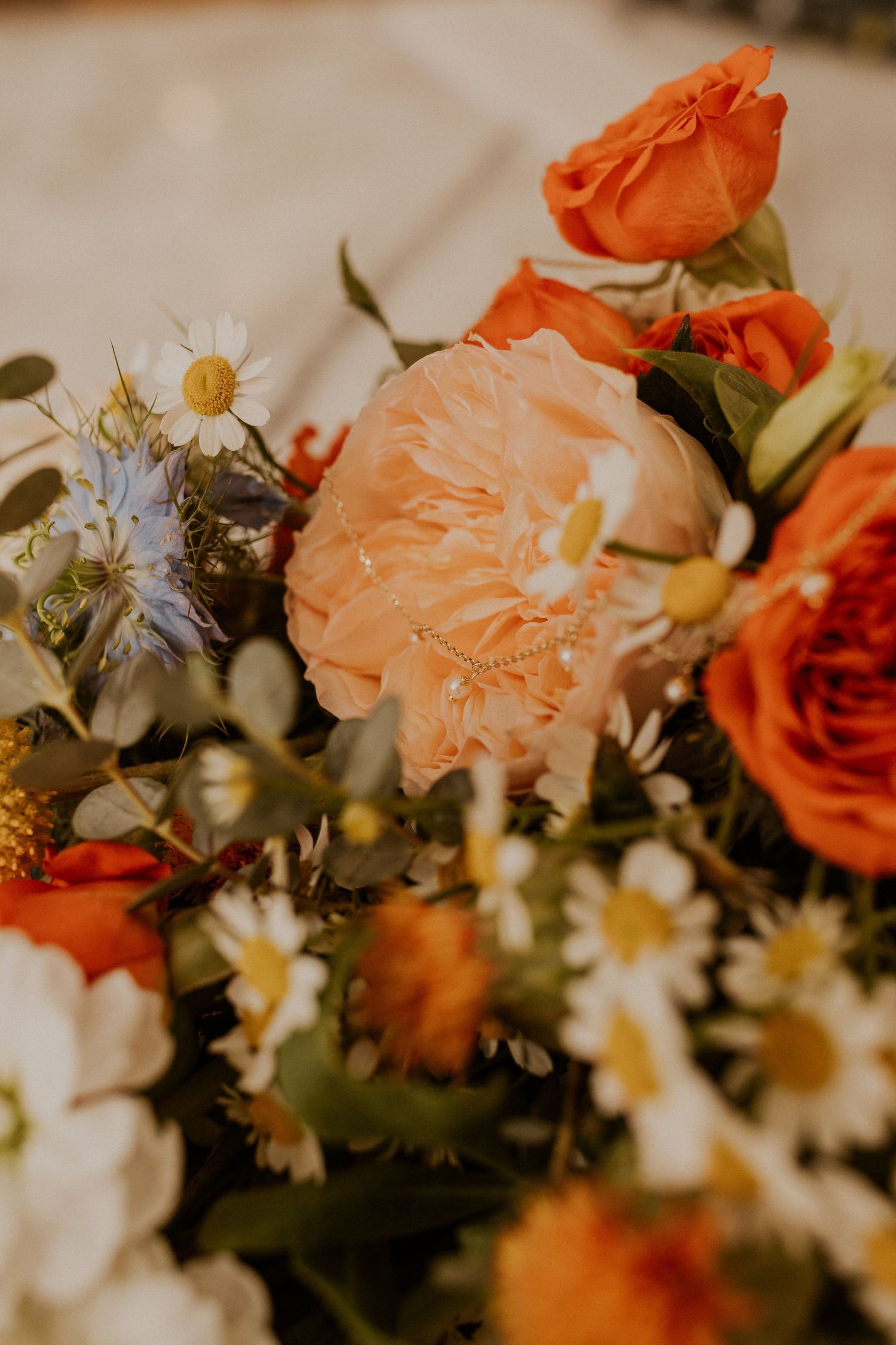 Close-up of orange and peach floral wedding arrangements with daisies.