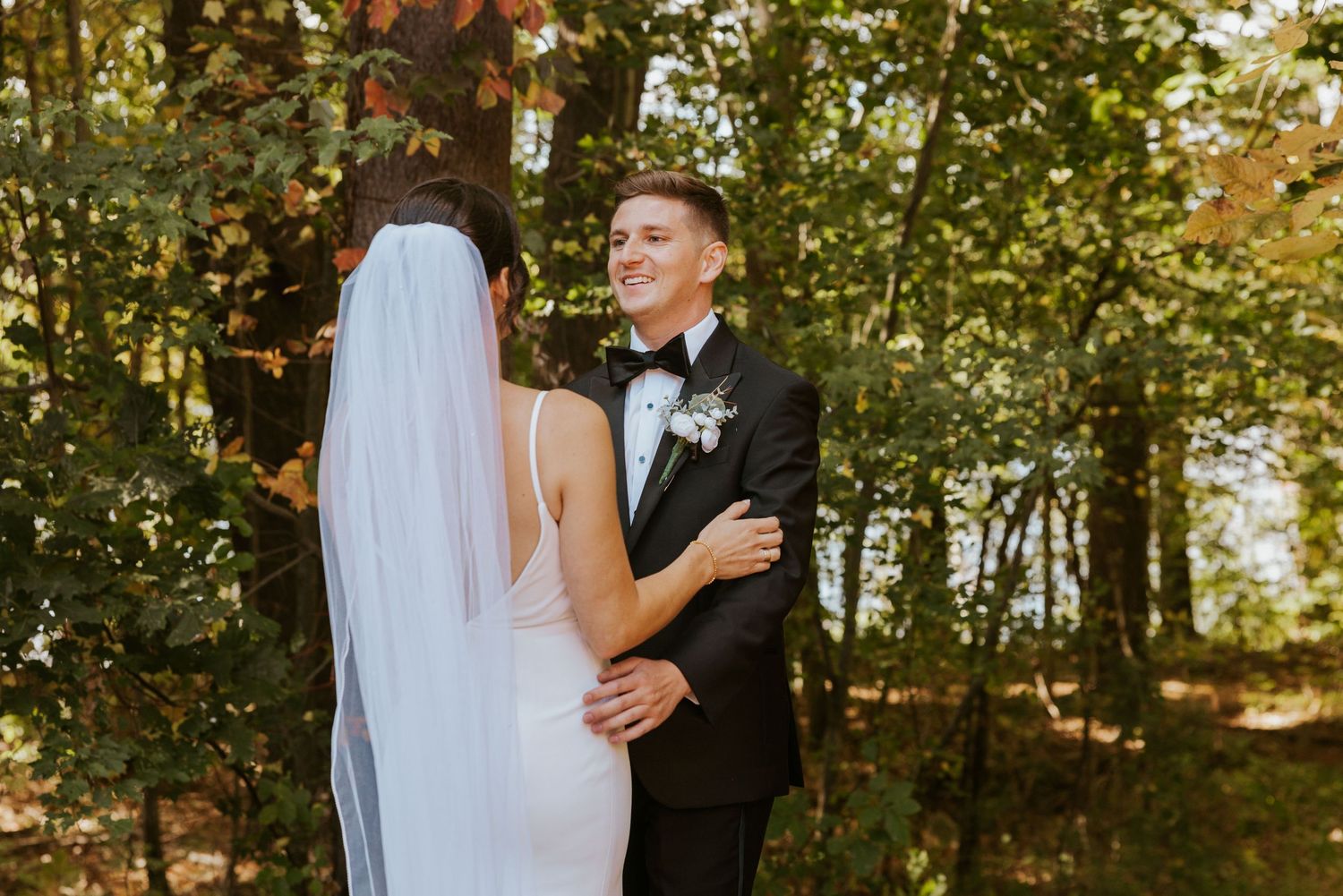 Bride and groom sharing an emotional first look moment surrounded by colorful fall foliage.