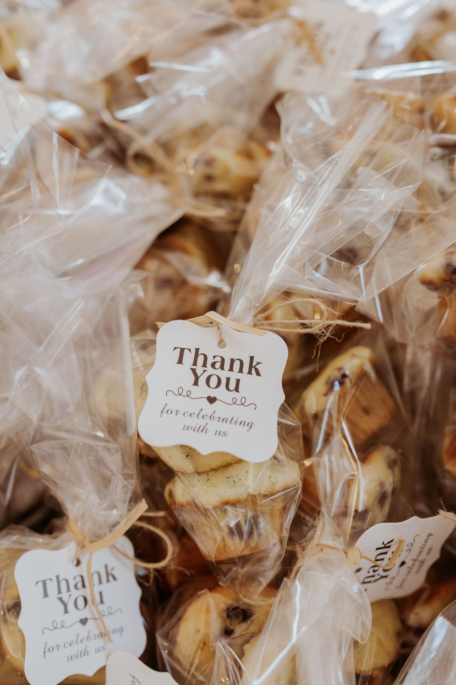 Cellophane bags of chocolate chip cookies tied with thank you tags as wedding guest favors.