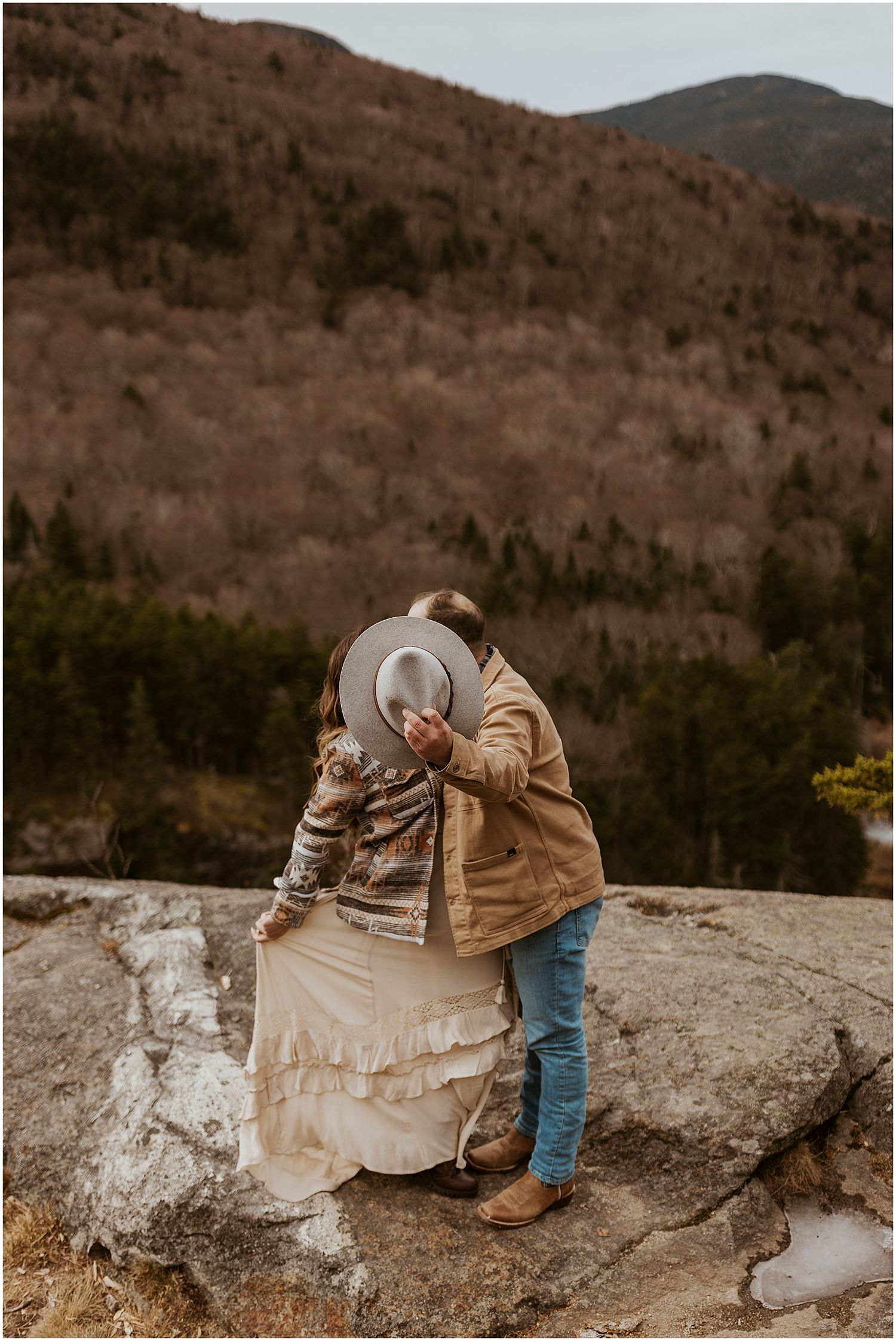 Couple sharing romantic moment on mountain overlook during autumn proposal.
