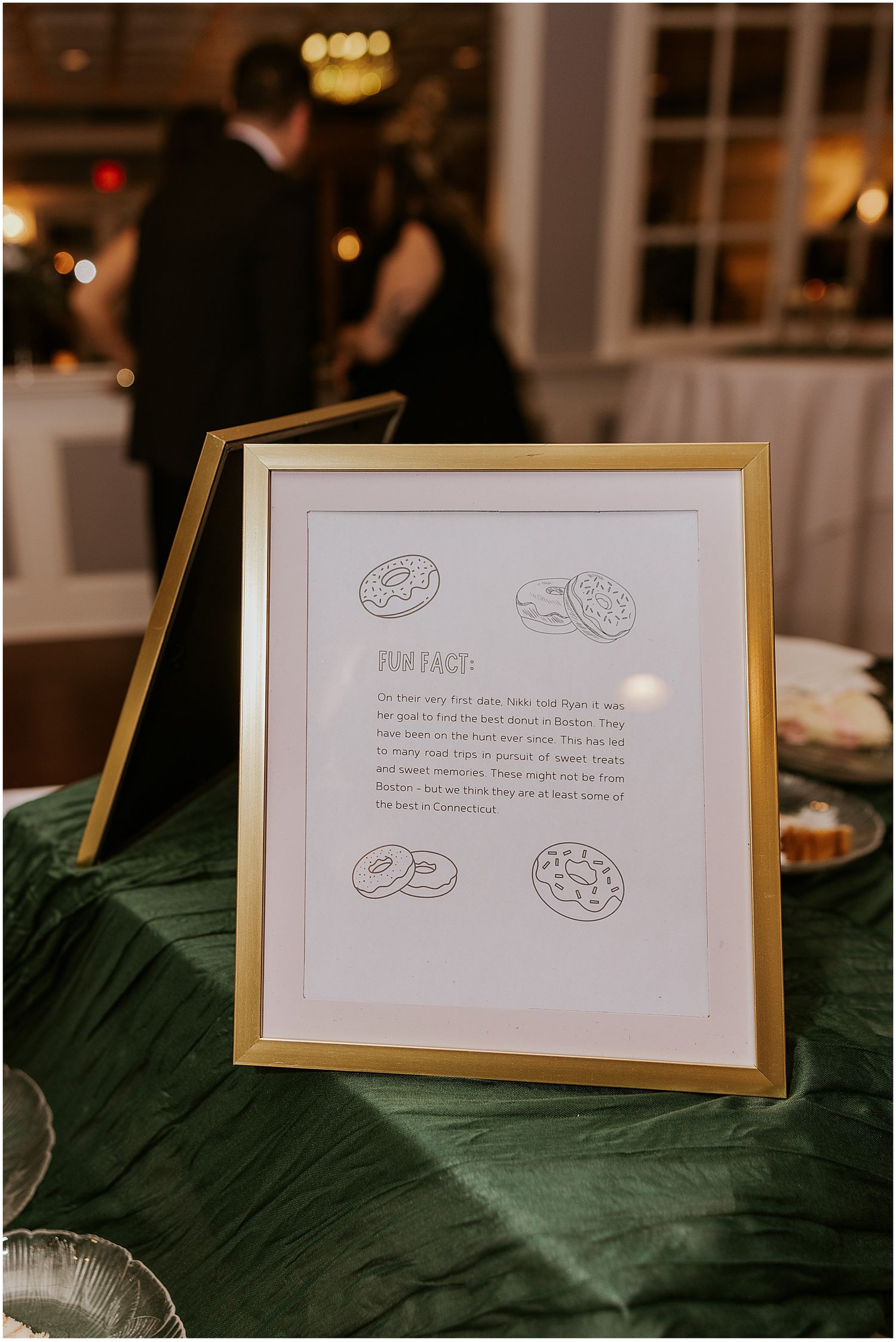Wedding menu cards with donut illustrations displayed on a green tablecloth.