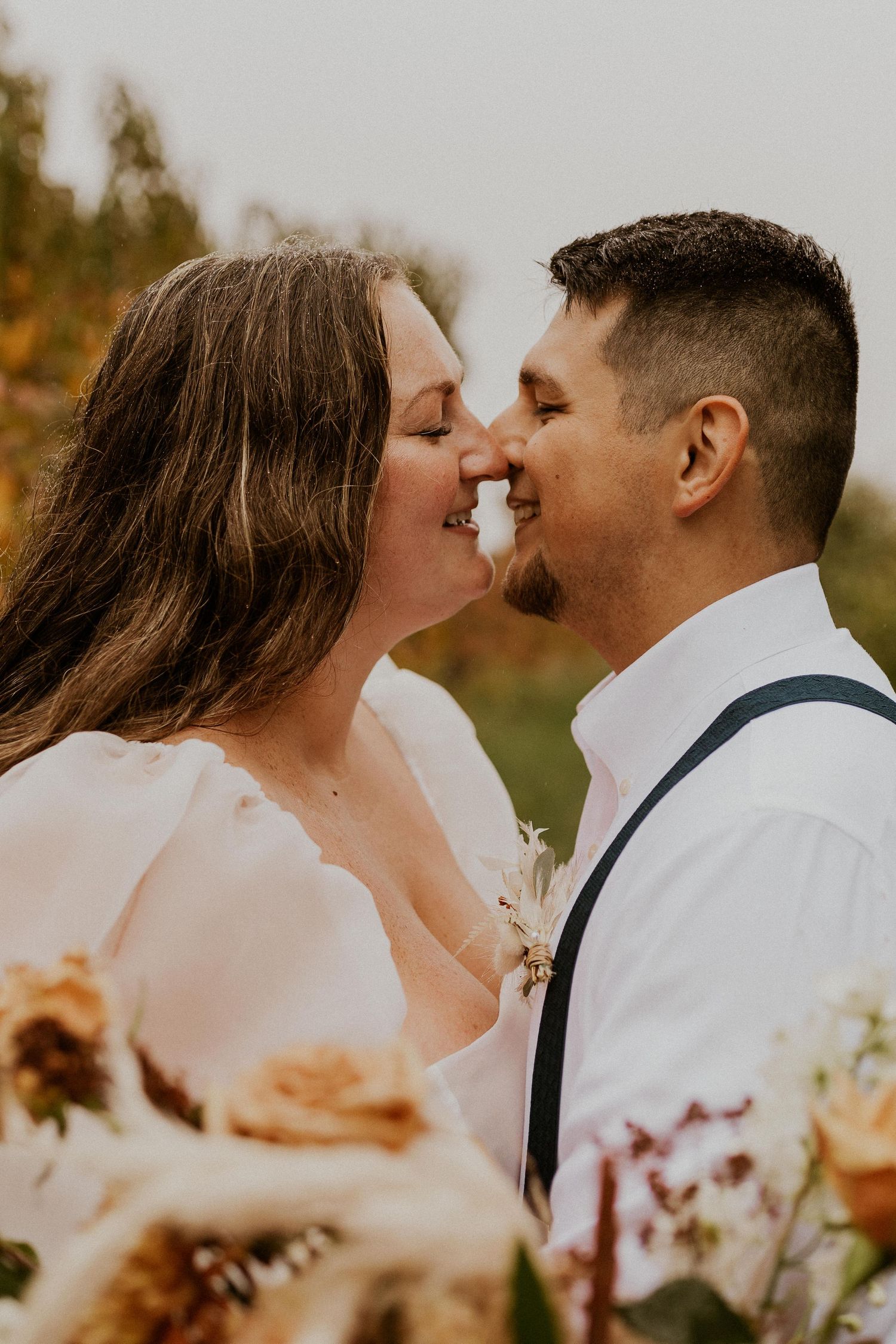 Terise and Jose kissing in between the rows of apple trees at Carter Hill Orchard in Concord New Hampshire]