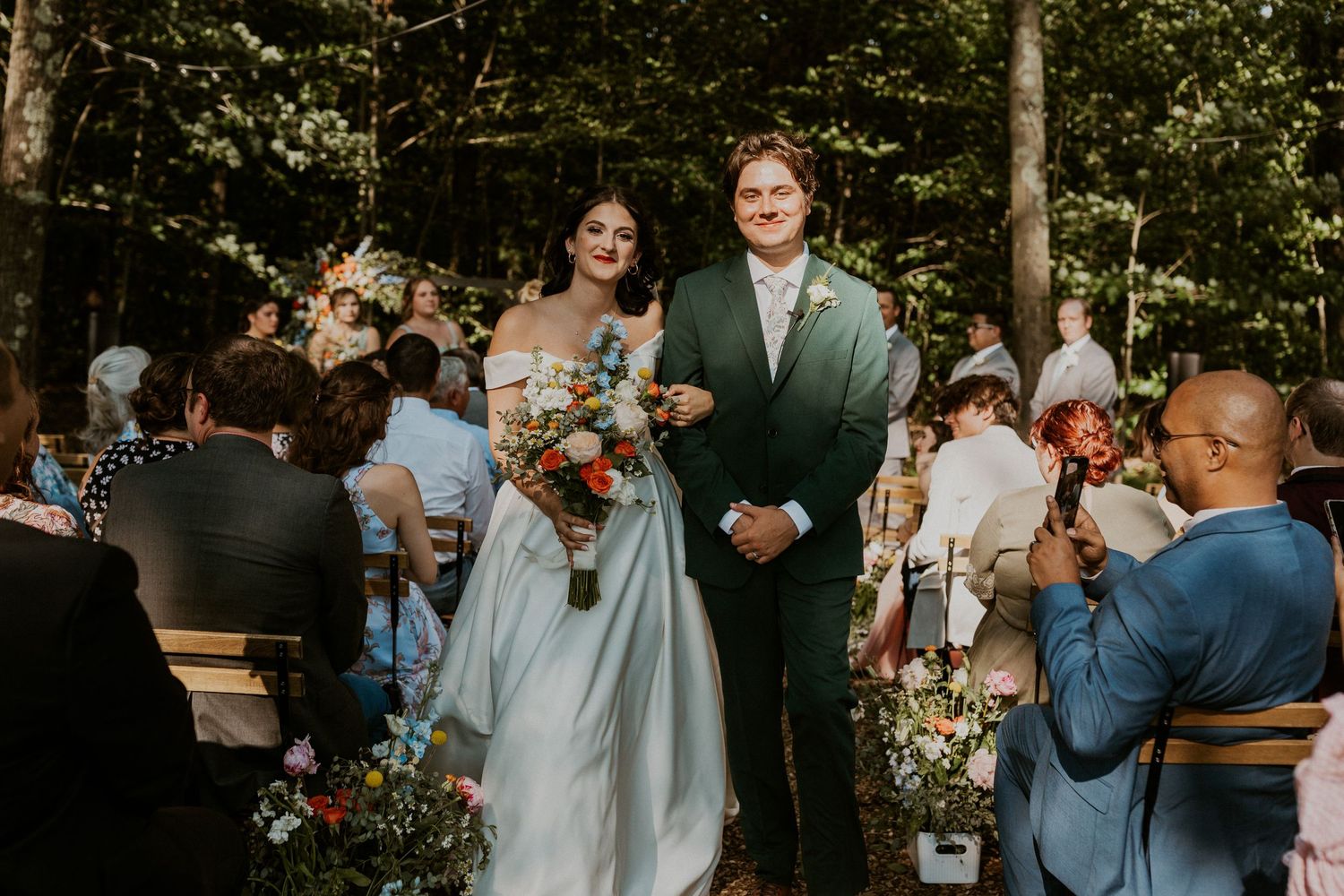 Wedding party celebrating outdoors in a garden setting with light blue bridesmaid dresses.