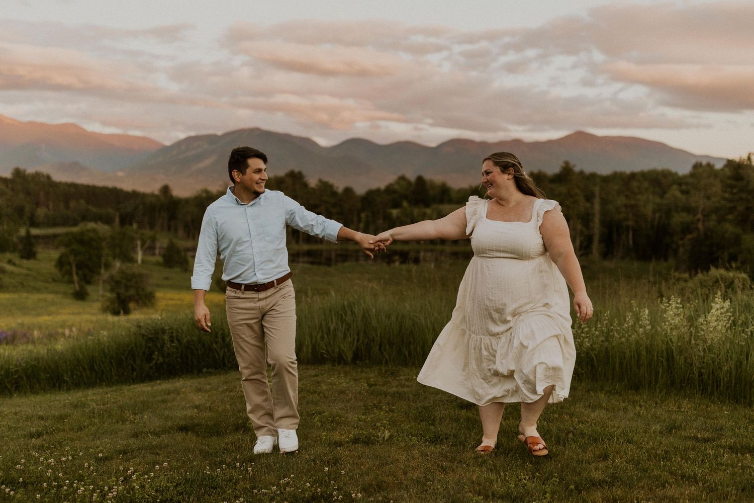 Terise and Jose playfully walking together in a lupine field in Sugar Hill NH during their engagement photos.
