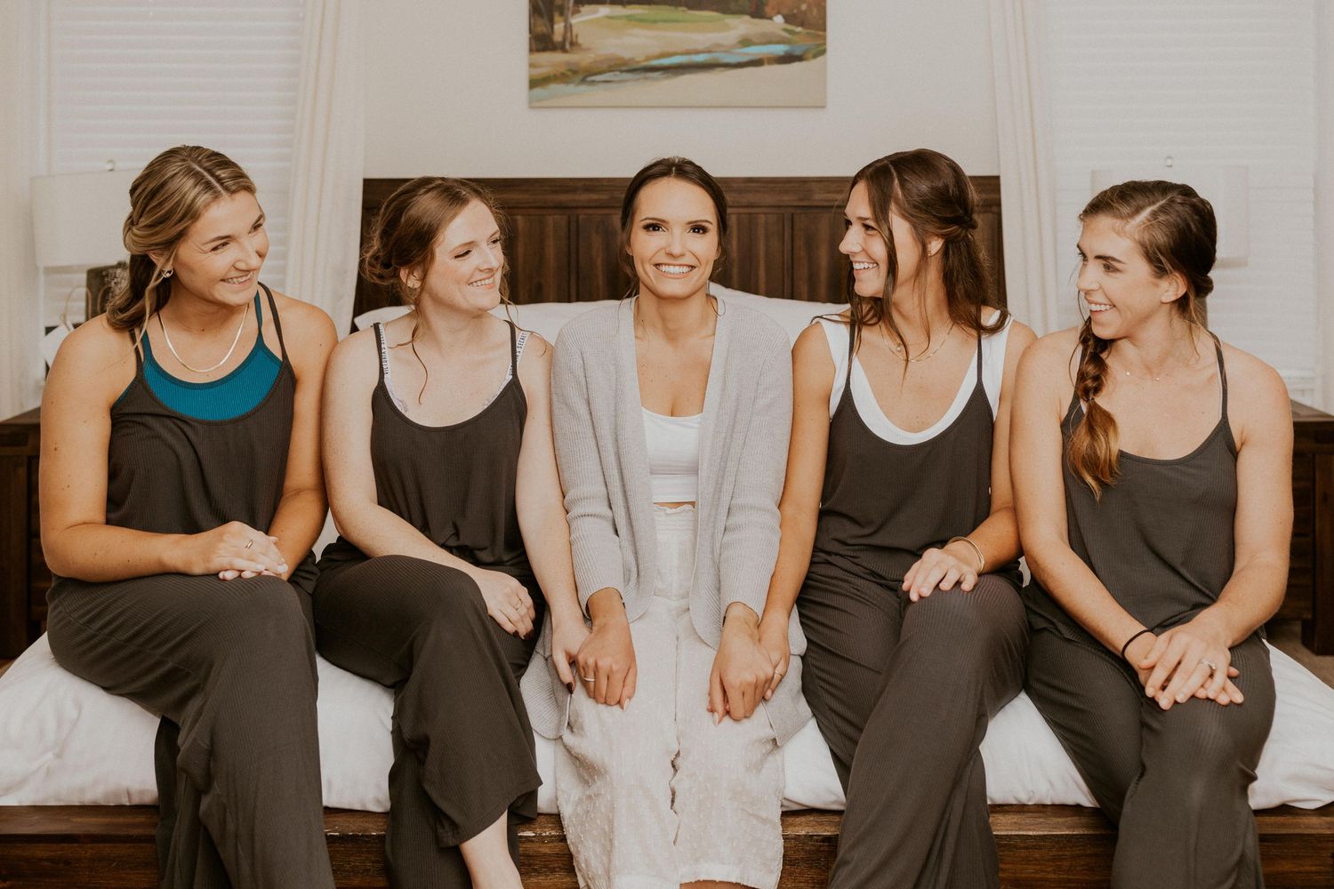 Abbie and her bridesmaids sitting together on the edge of the bed for a pajama photo before they all changed.