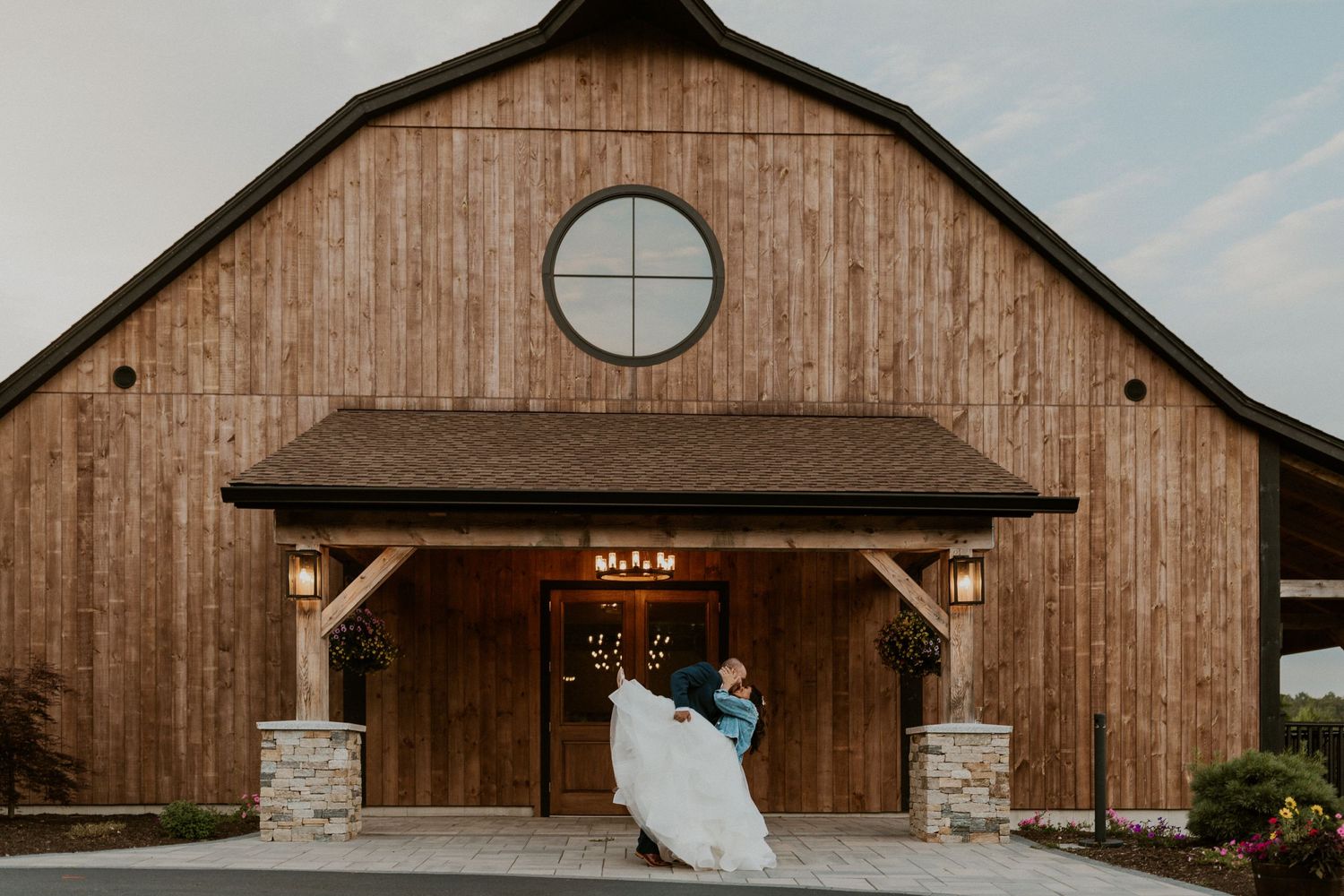 Rustic wooden barn wedding venue with stone accents and large windows.