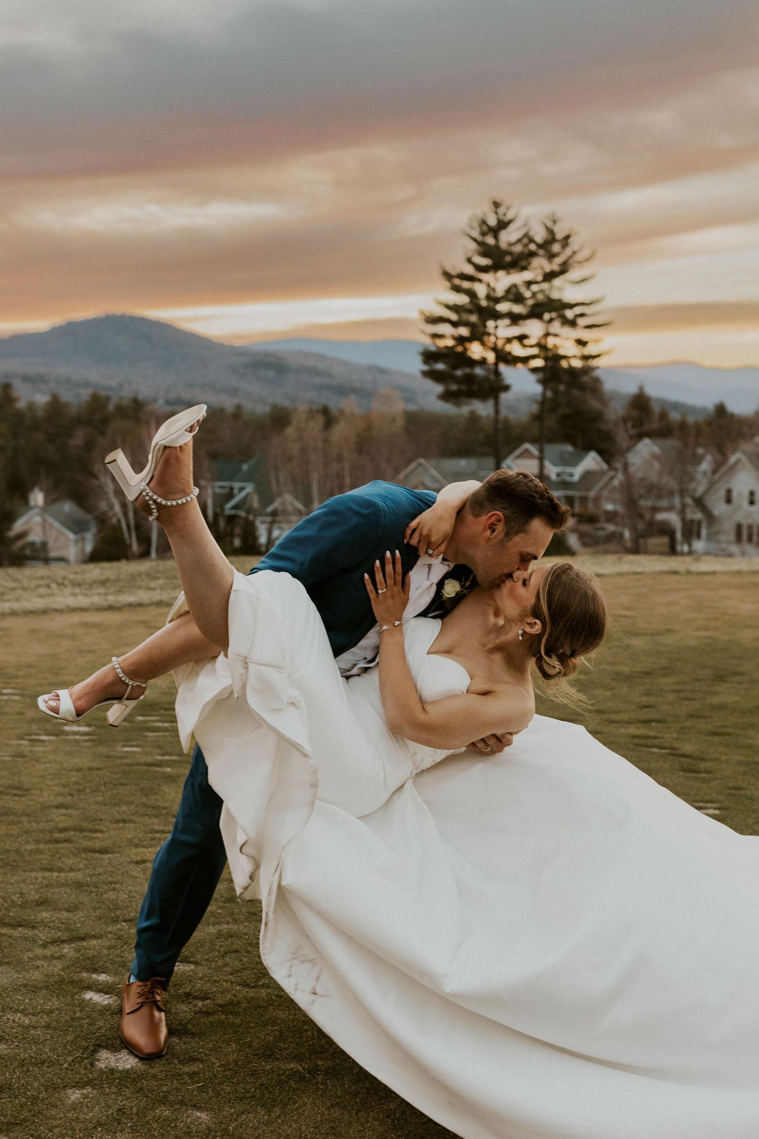 Fun sunset portrait of Andrew holding and dipping Kendra down while kissing her at Owl's Nest Resort in Thornton NH