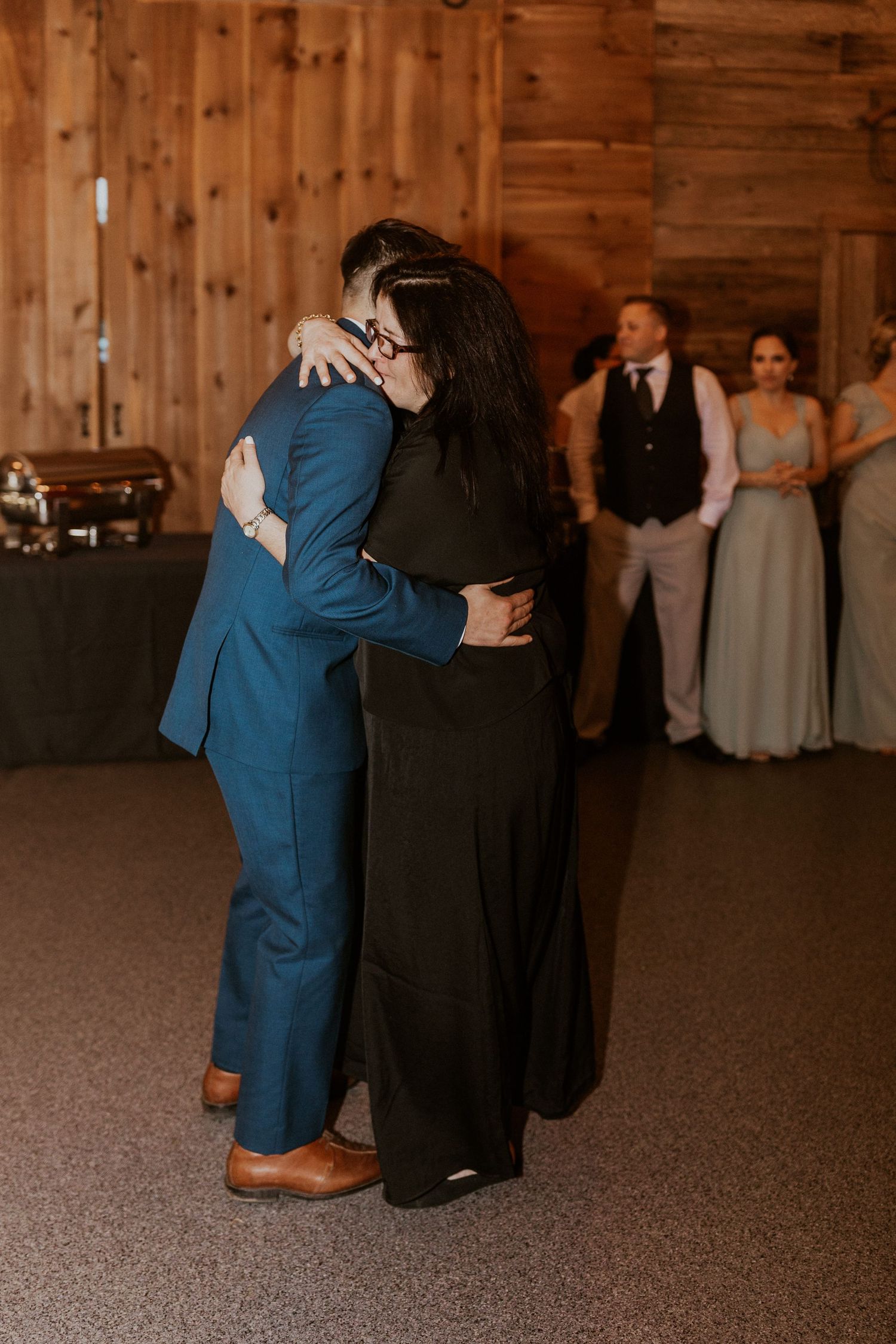Emotional dance moments during a wedding reception in a rustic wooden barn venue.