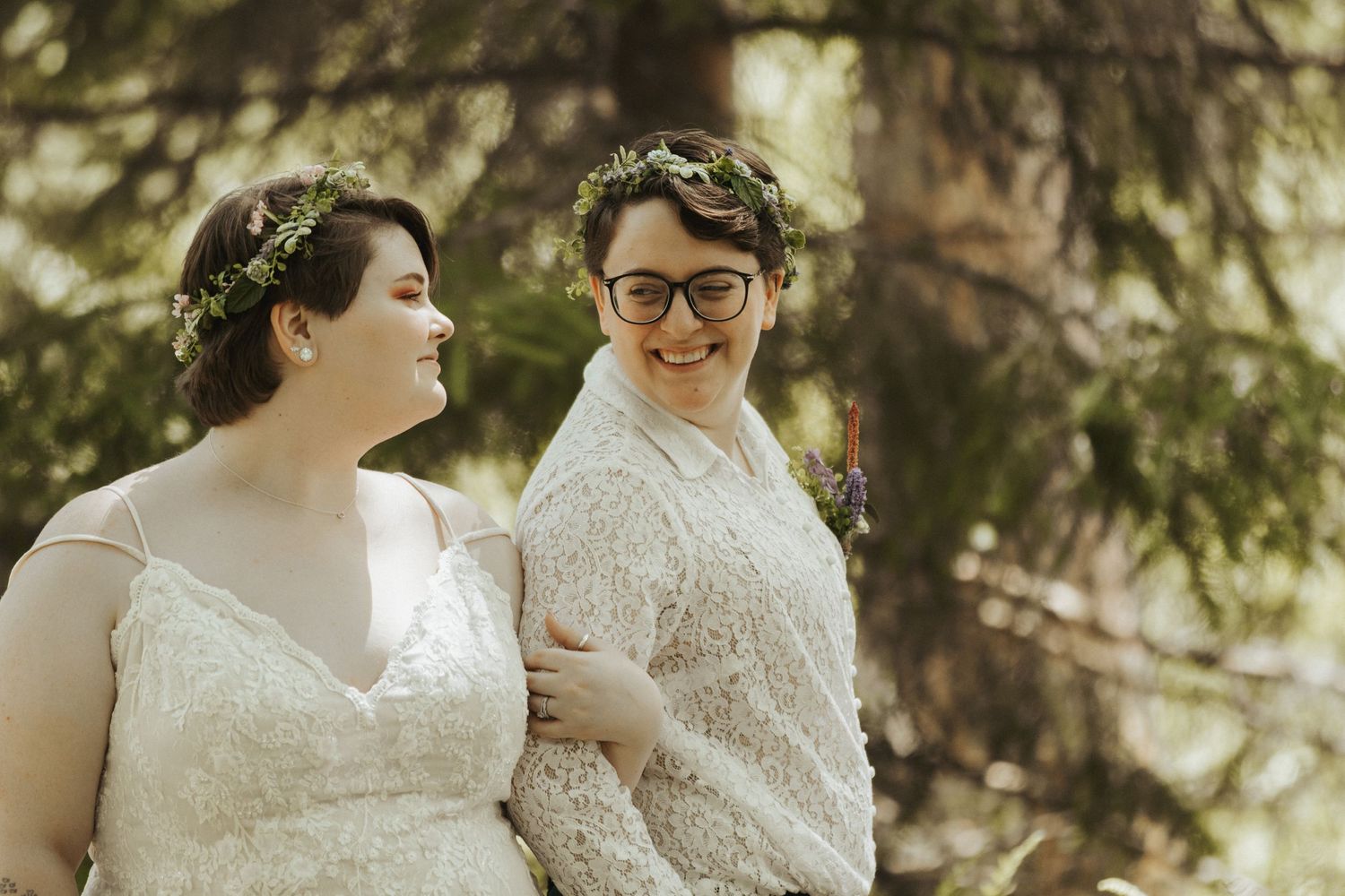 Two people in white lace dresses share an intimate moment during their wedding celebration.