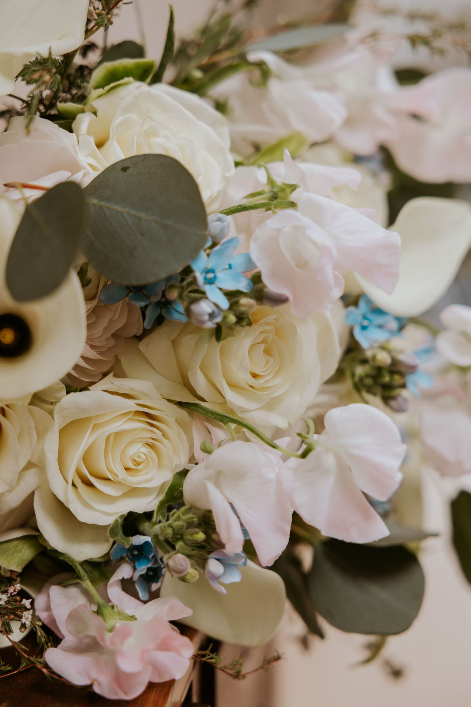 Delicate white roses and blue accents create an elegant wedding bouquet arrangement.