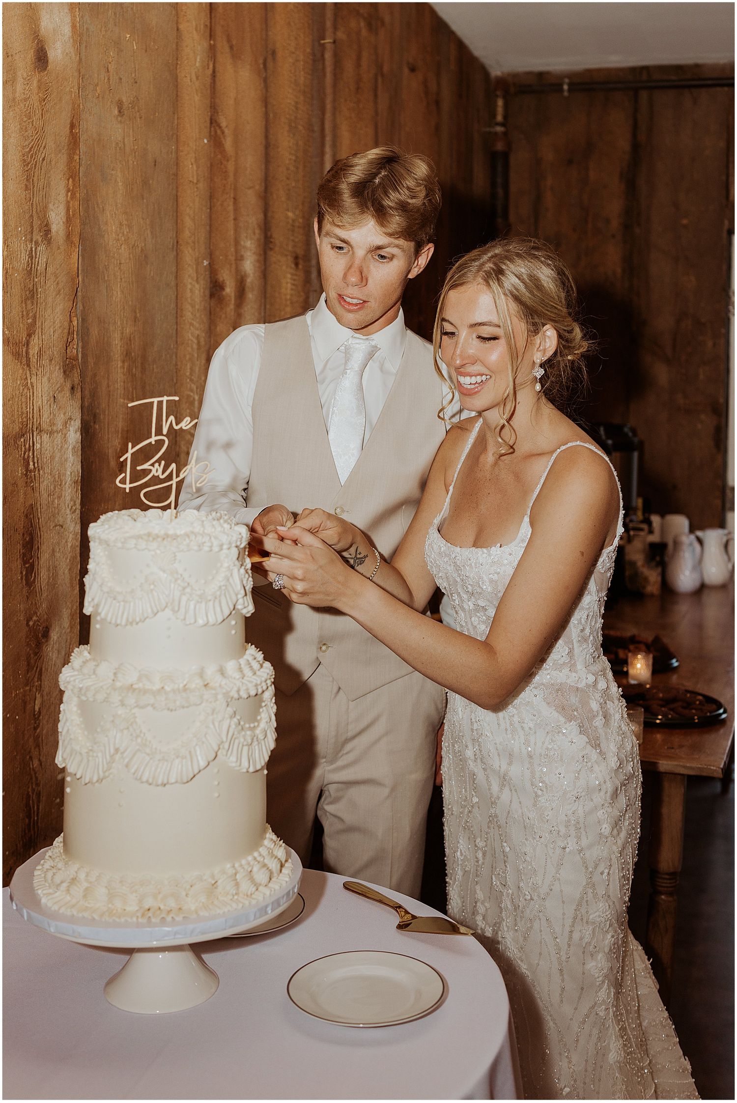 A couple cutting their elegant white wedding cake together at their reception.
