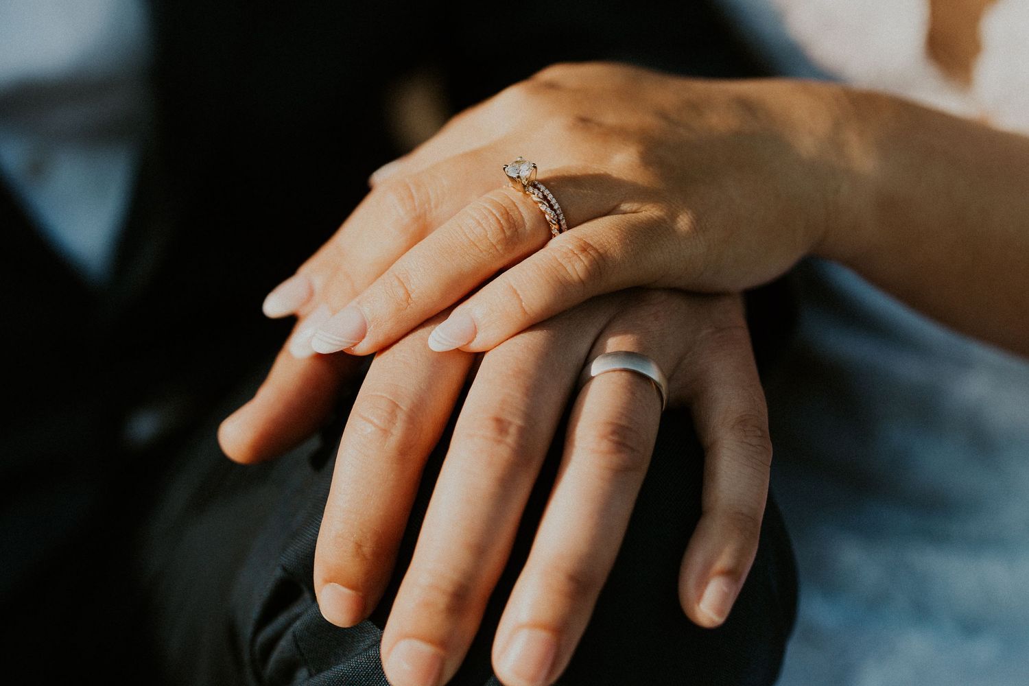Chrissy and Mike's hands placed together with a focus on their rings.