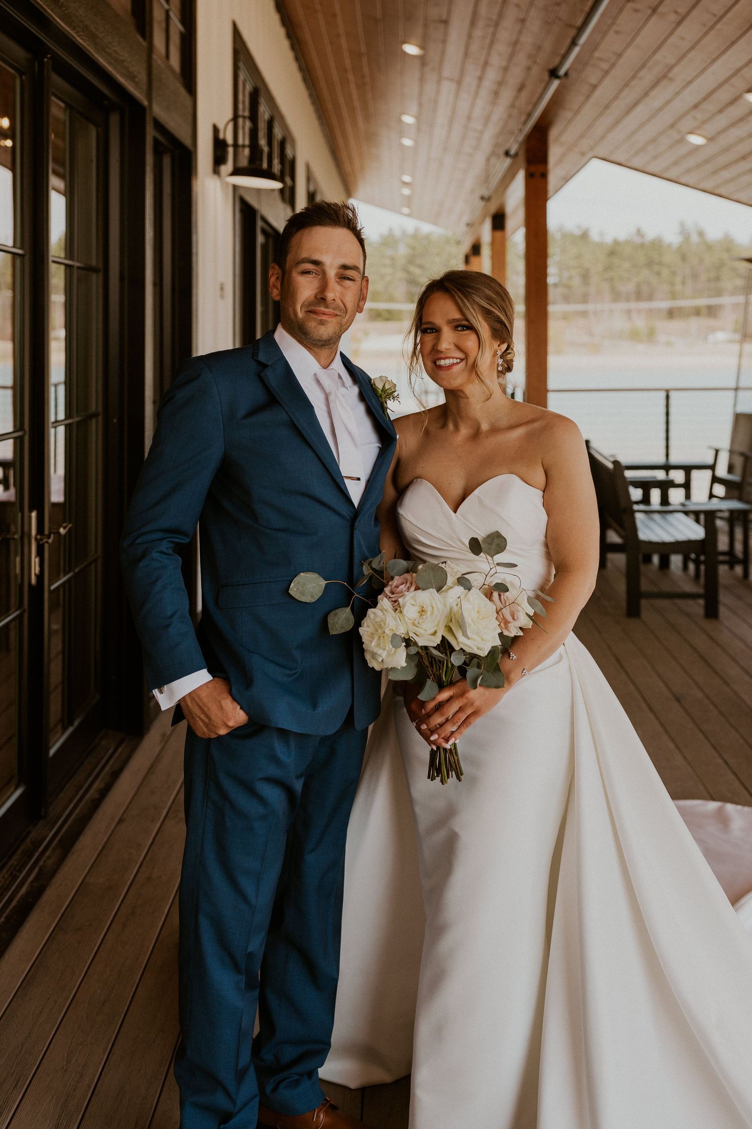Kendra and Andrew smiling for a wedding portrait at the Owl's Nest Lake House.